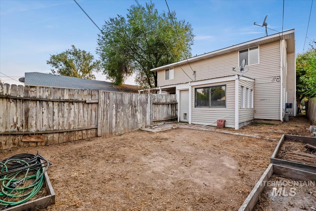 Back of house featuring a fenced backyard, a patio area, and a vegetable garden