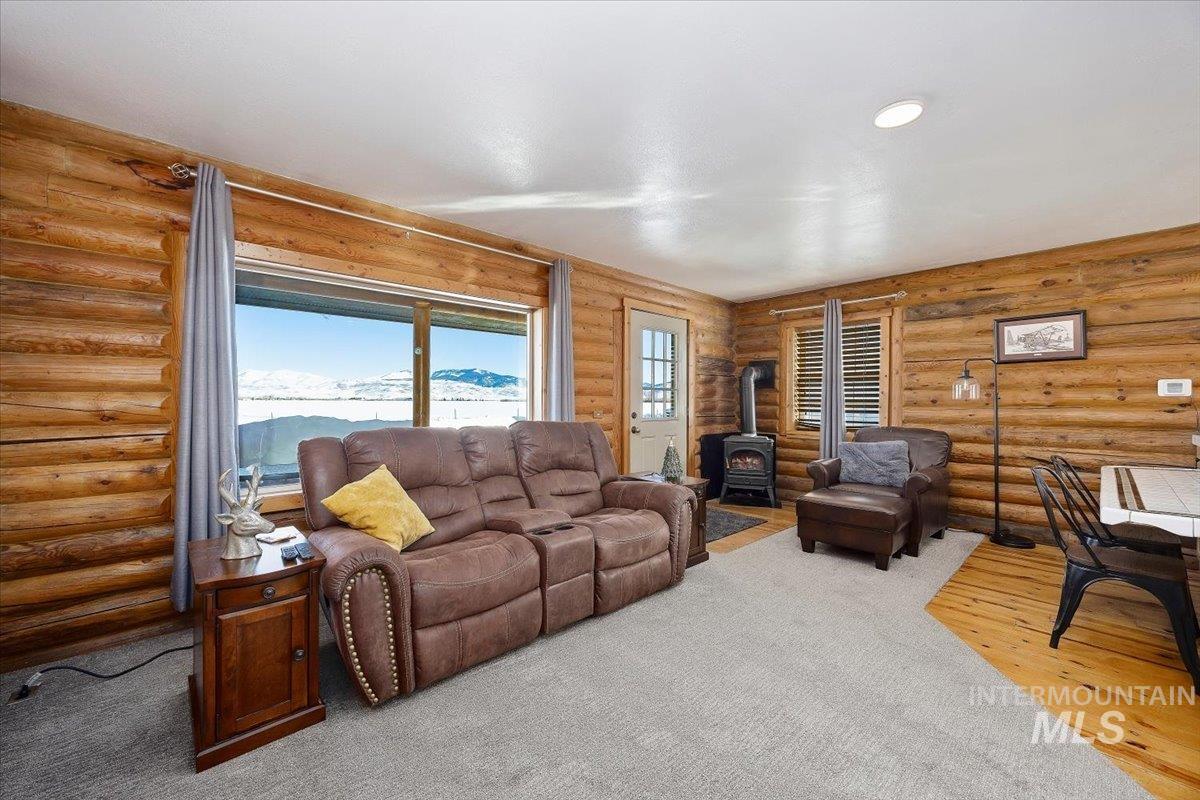 Living area featuring a wood stove, wood finished floors, rustic walls, and recessed lighting