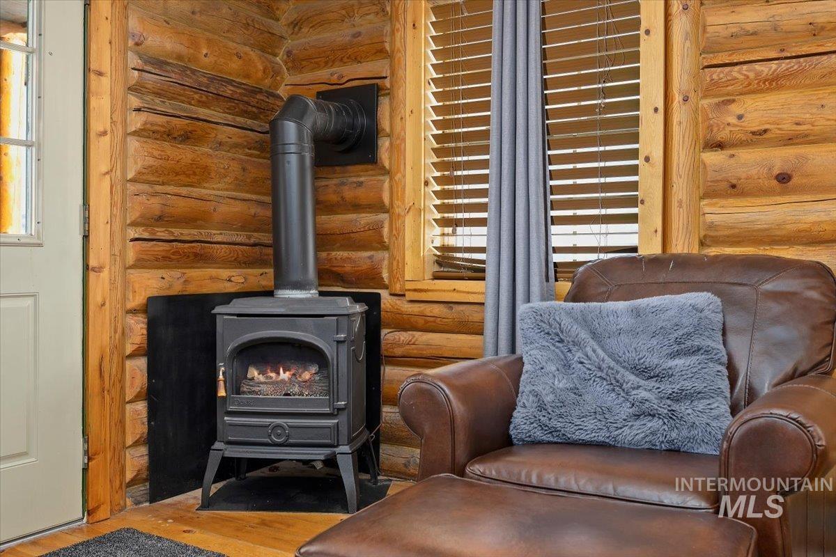 Living area with log walls, a wood stove, and wood finished floors