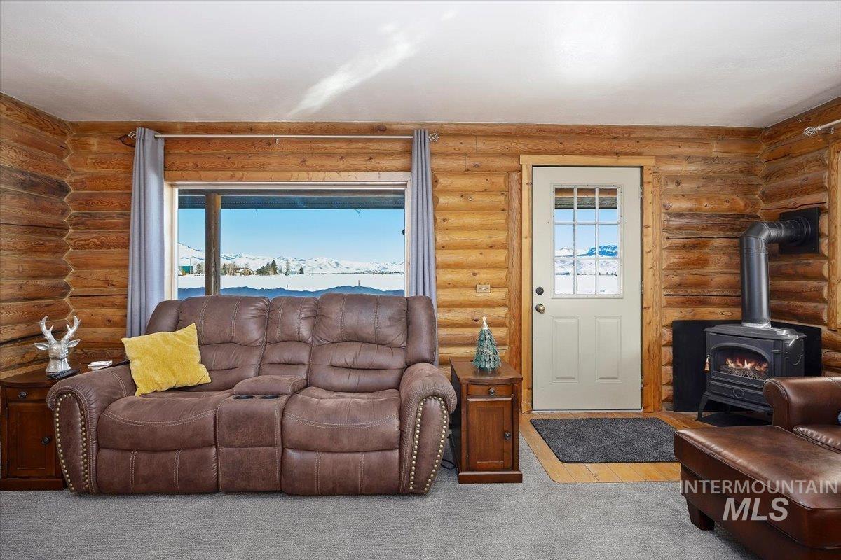 Living room with a wood stove, carpet floors, and log walls