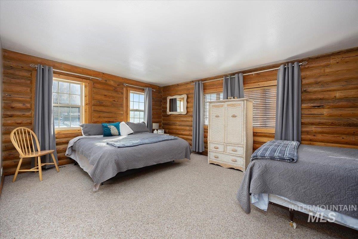 Carpeted bedroom featuring rustic walls