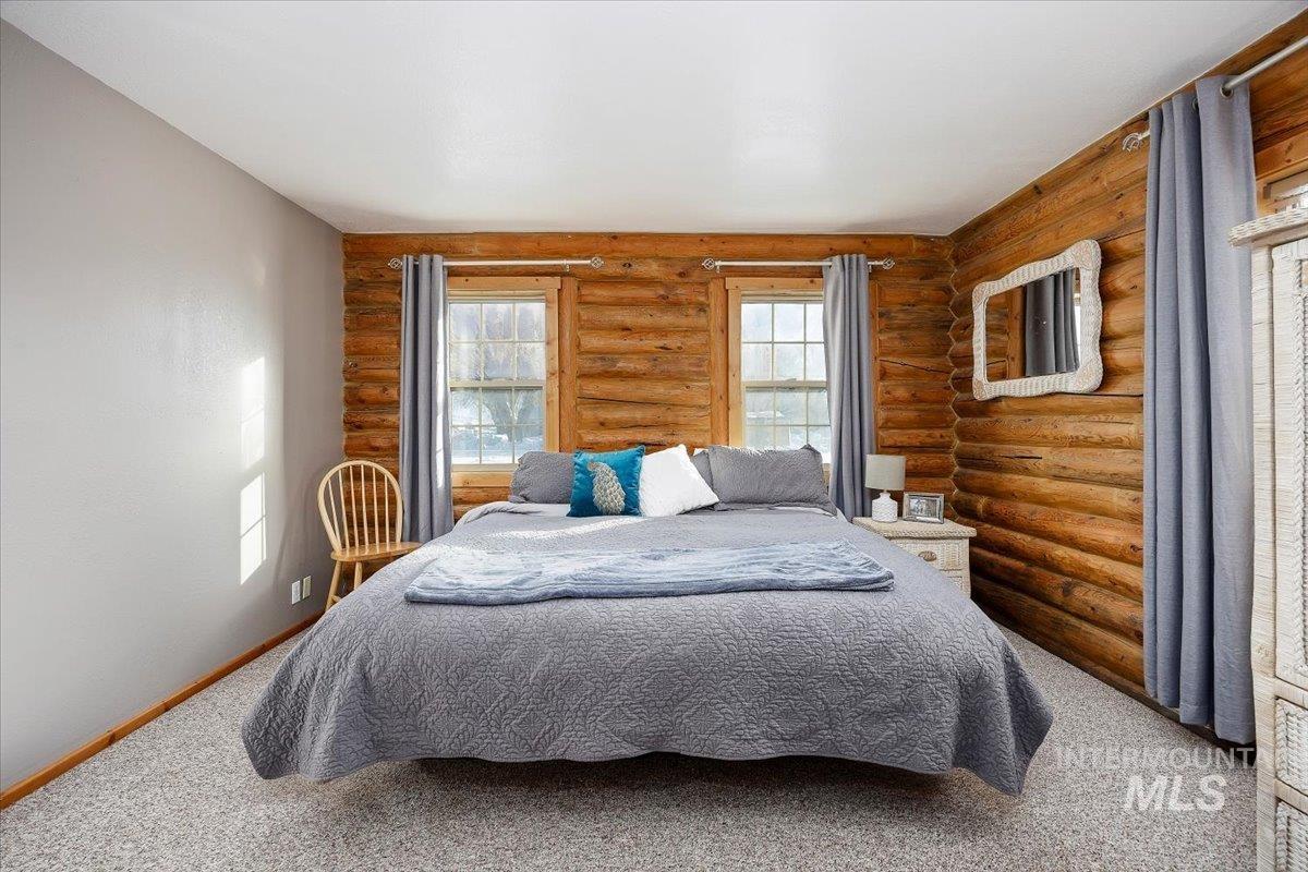 Carpeted bedroom with log walls