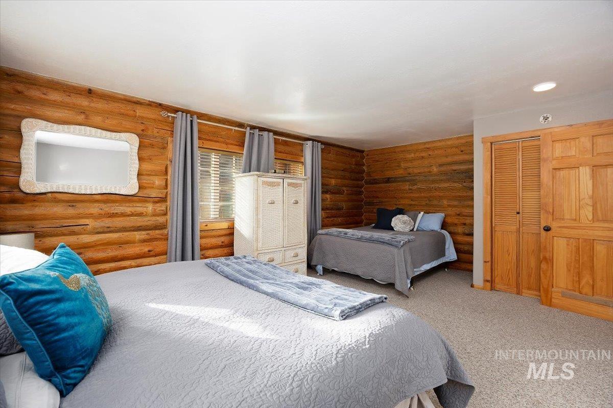 Carpeted bedroom with a closet and log walls