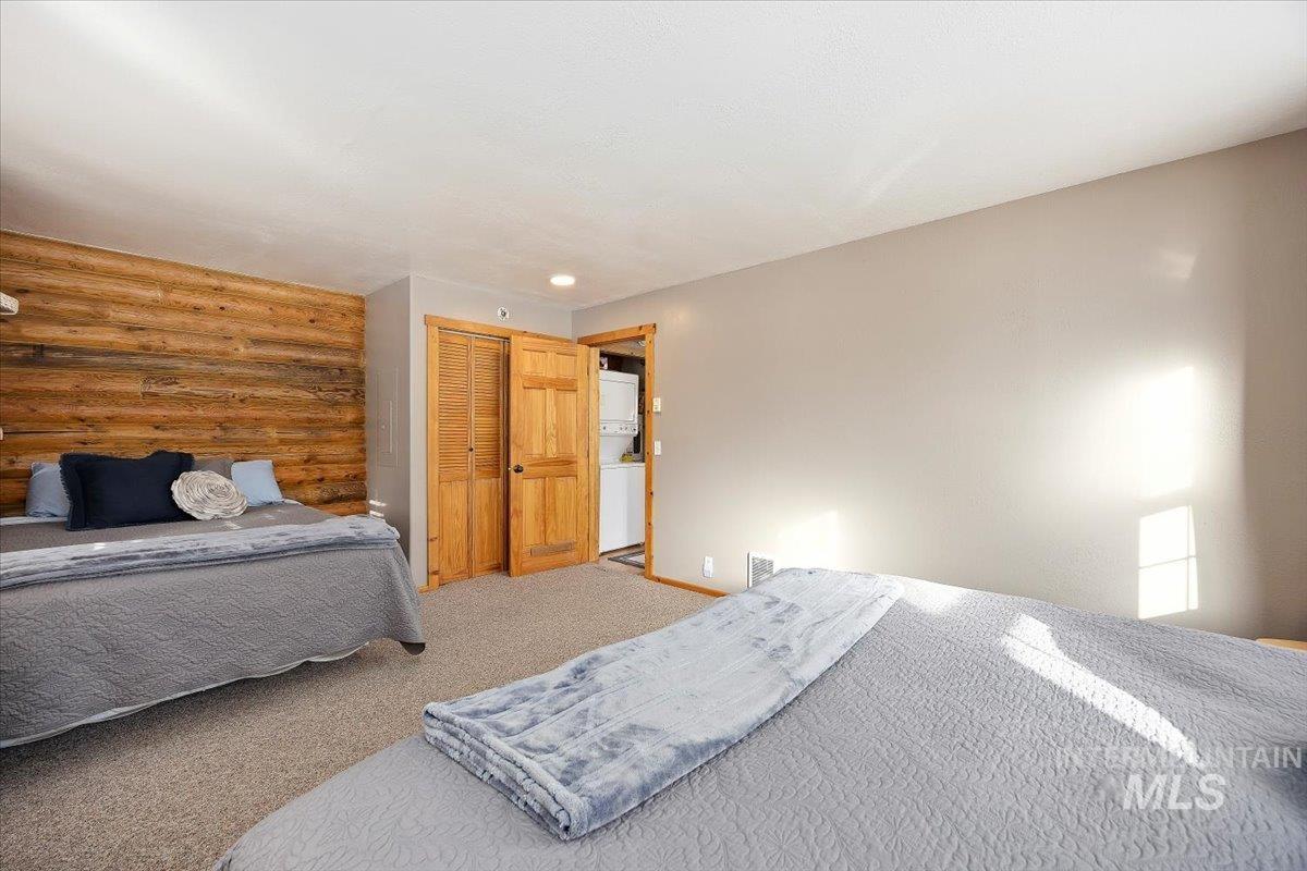 Bedroom featuring carpet, log walls, and a closet