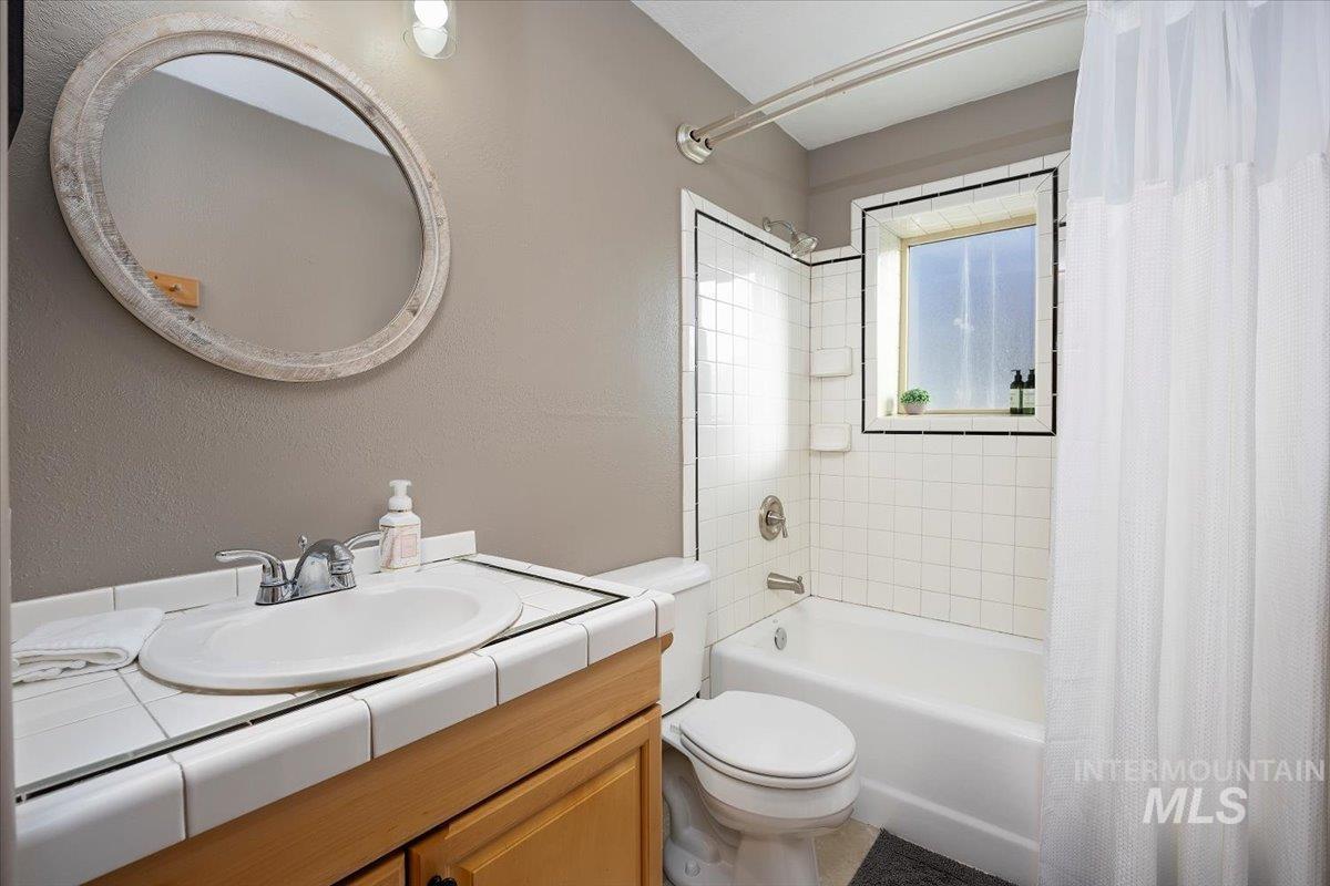 Full bath featuring shower / bath combination with curtain, vanity, and a textured wall