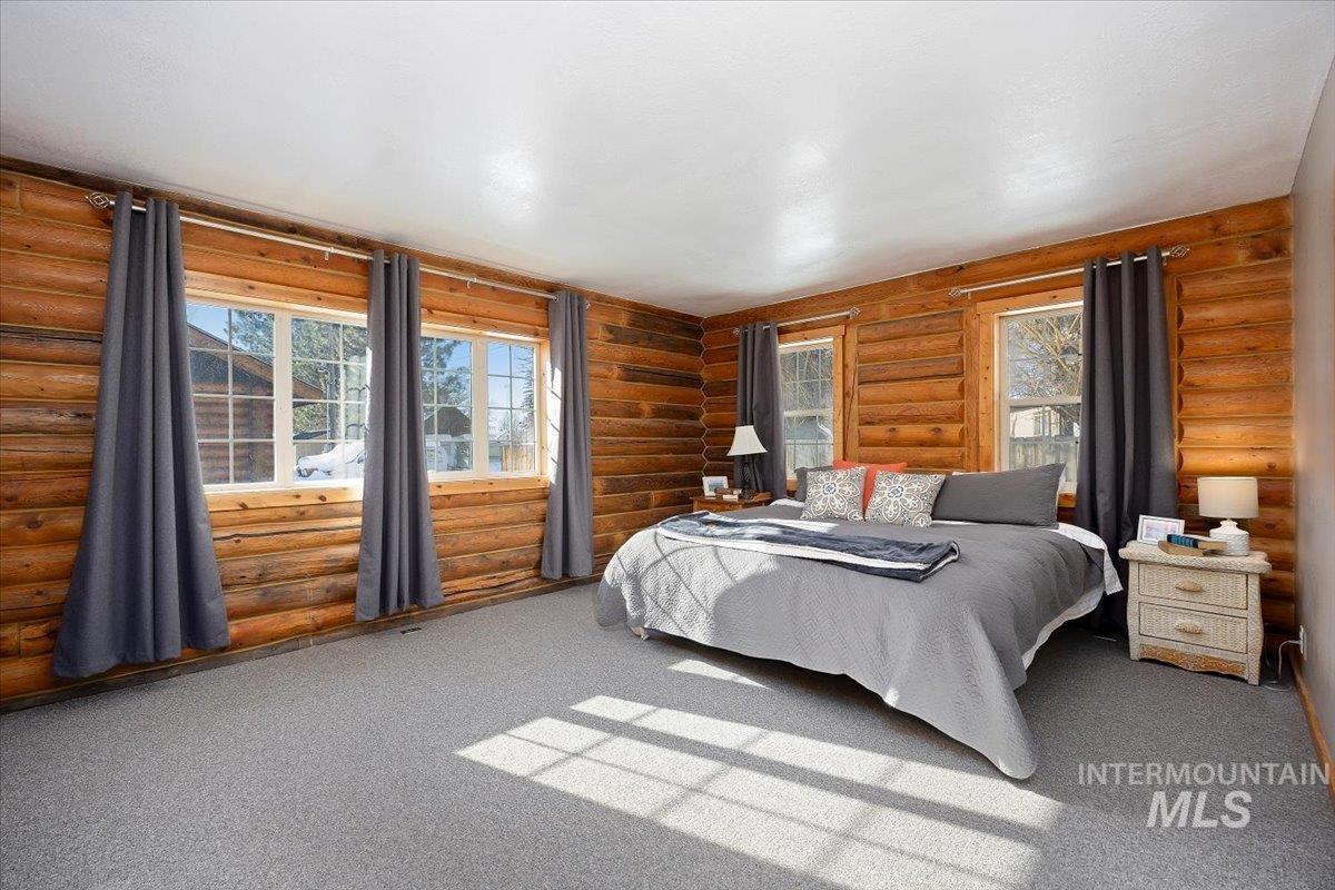 Bedroom featuring carpet and log walls