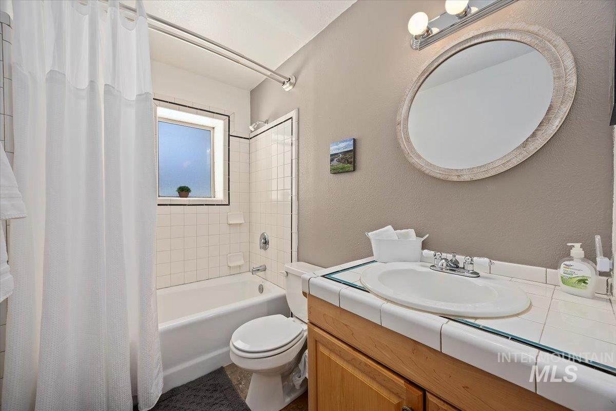 Bathroom featuring shower / bath combo, vanity, and a textured wall