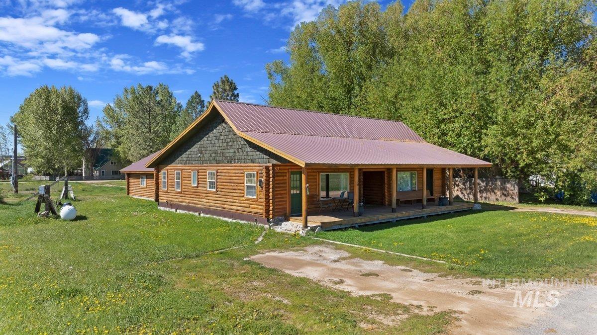 Log home featuring a porch, a front lawn, and a metal roof