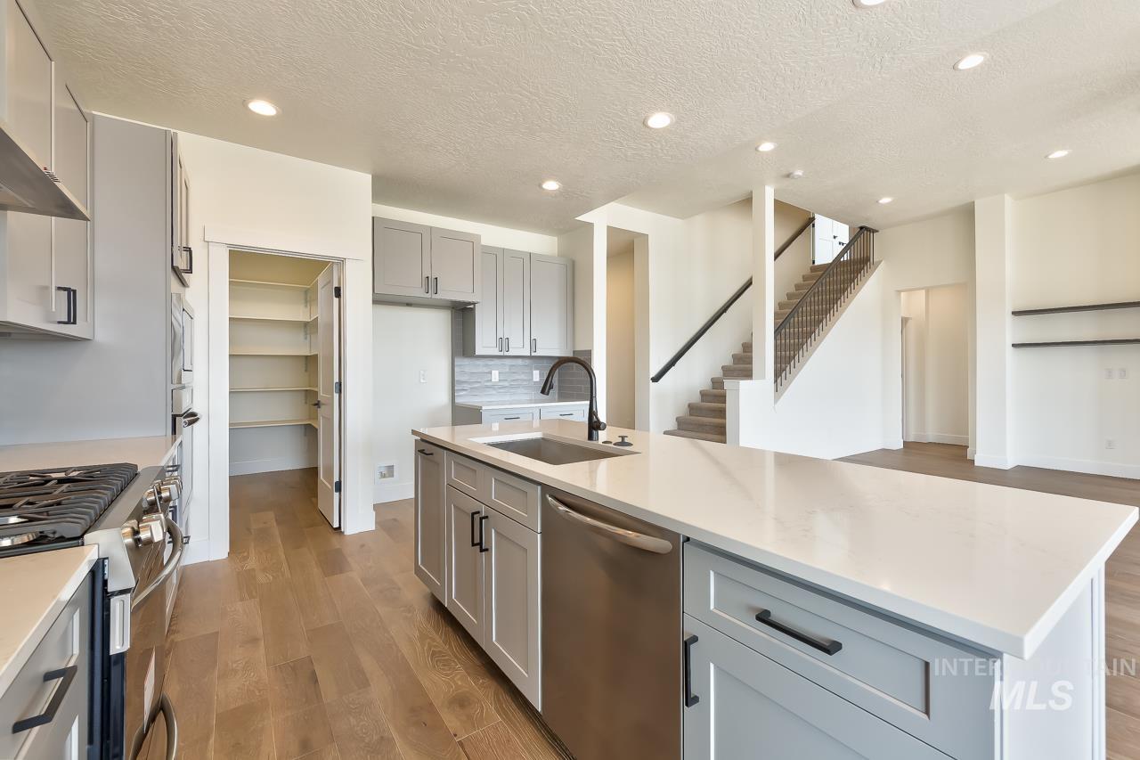 Kitchen featuring gray cabinetry, a textured ceiling, appliances with stainless steel finishes, light wood-type flooring, and recessed lighting