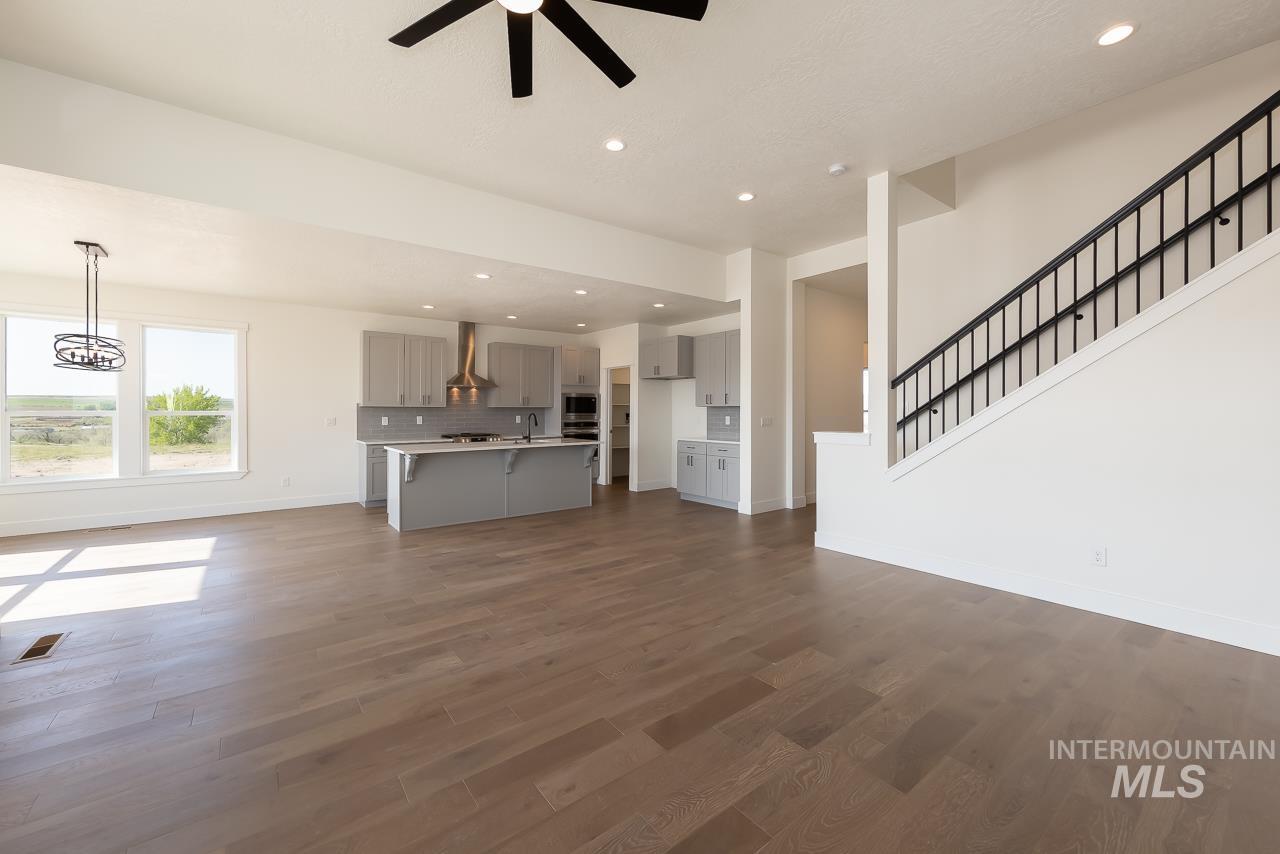 Unfurnished living room with recessed lighting, dark wood-style floors, stairs, and ceiling fan