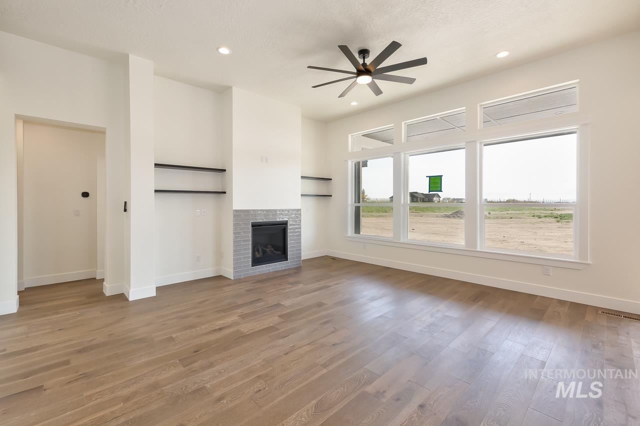 Unfurnished living room featuring light wood-style flooring, a fireplace, a ceiling fan, recessed lighting, and a textured ceiling