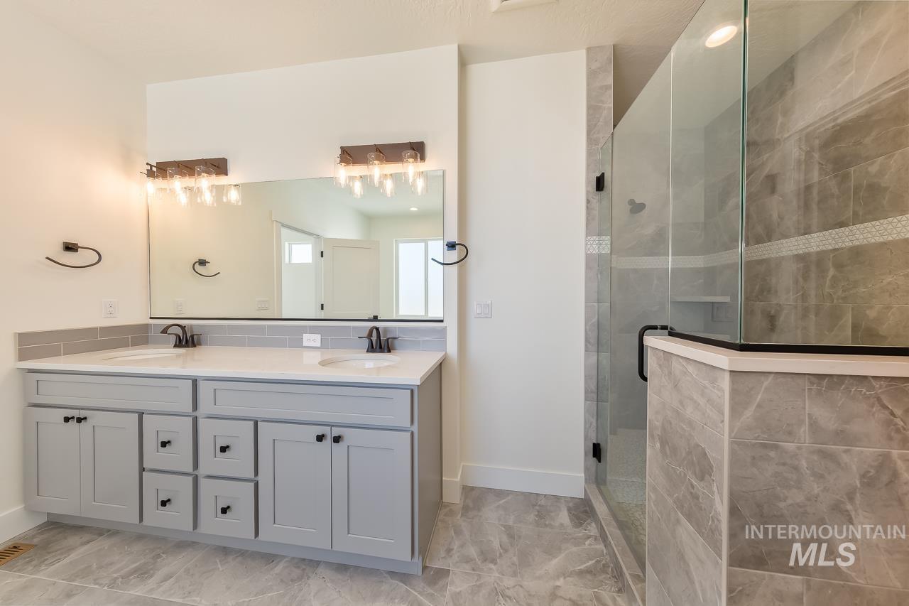 Full bathroom featuring double vanity and a shower stall