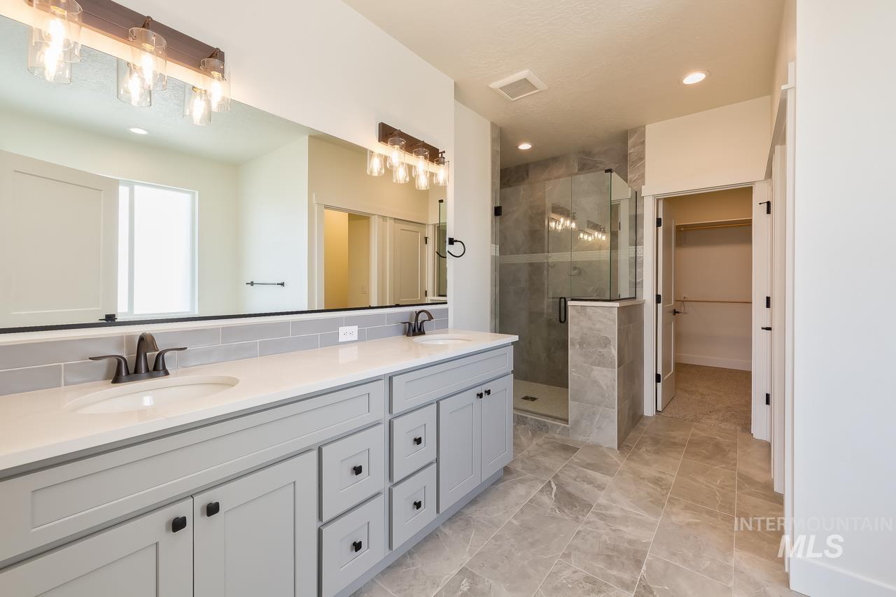 Bathroom with double vanity, a spacious closet, a stall shower, recessed lighting, and backsplash
