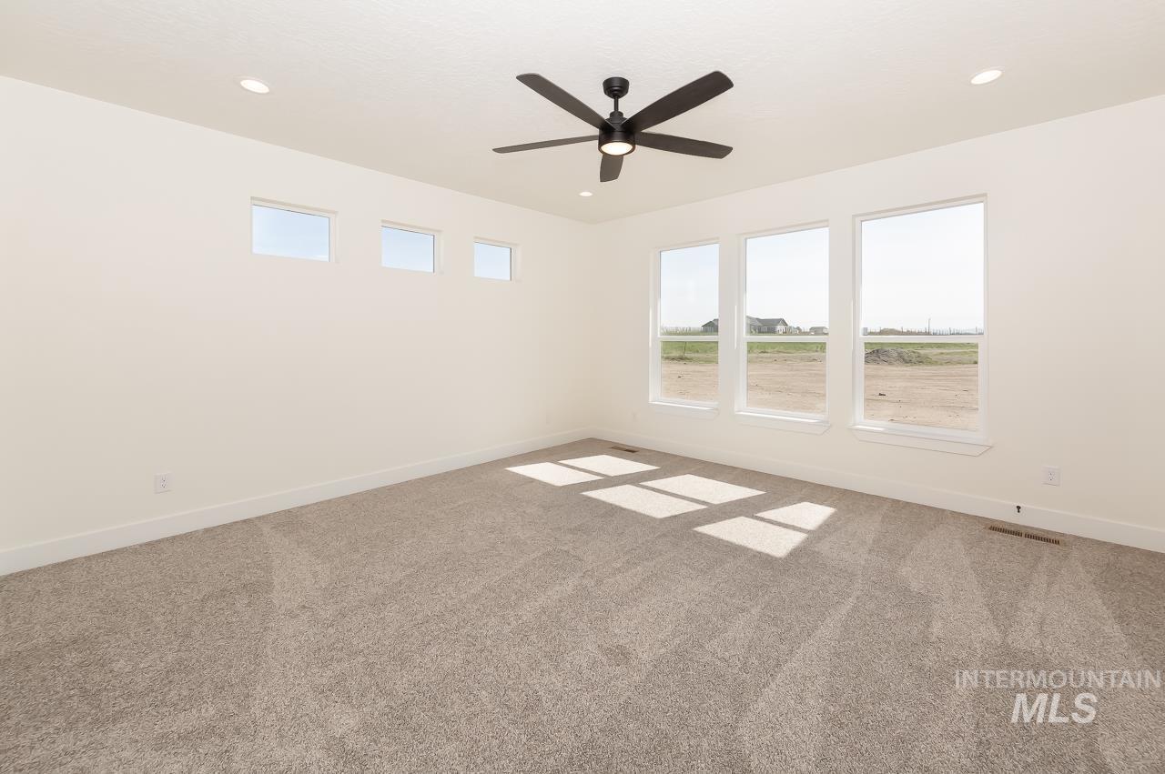 Empty room featuring light colored carpet, plenty of natural light, recessed lighting, and a ceiling fan