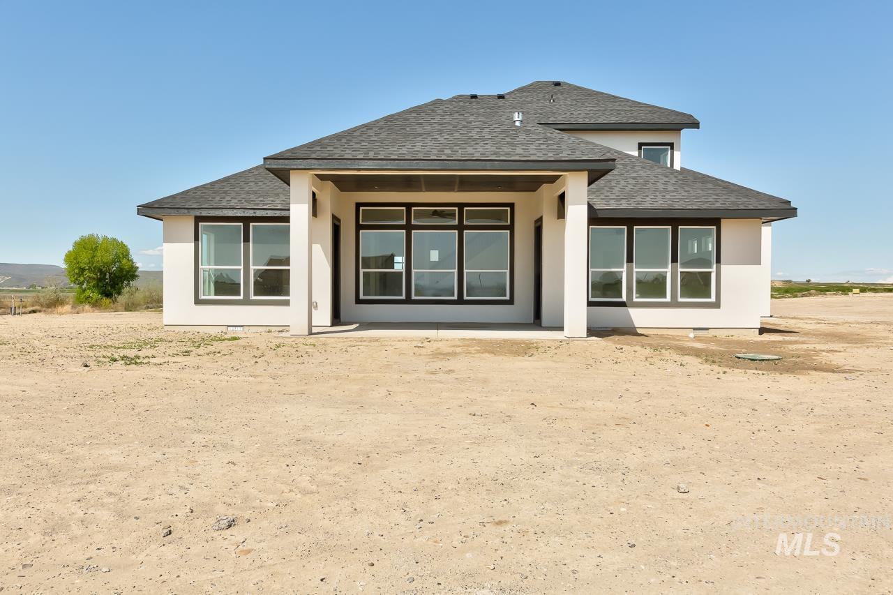 Back of property featuring a shingled roof, a patio, and stucco siding