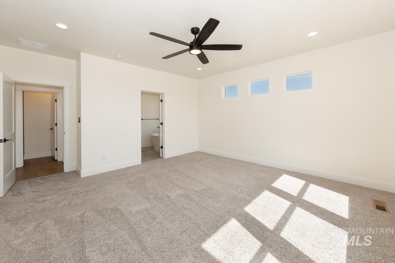 Unfurnished bedroom with ensuite bathroom, light colored carpet, recessed lighting, and a ceiling fan