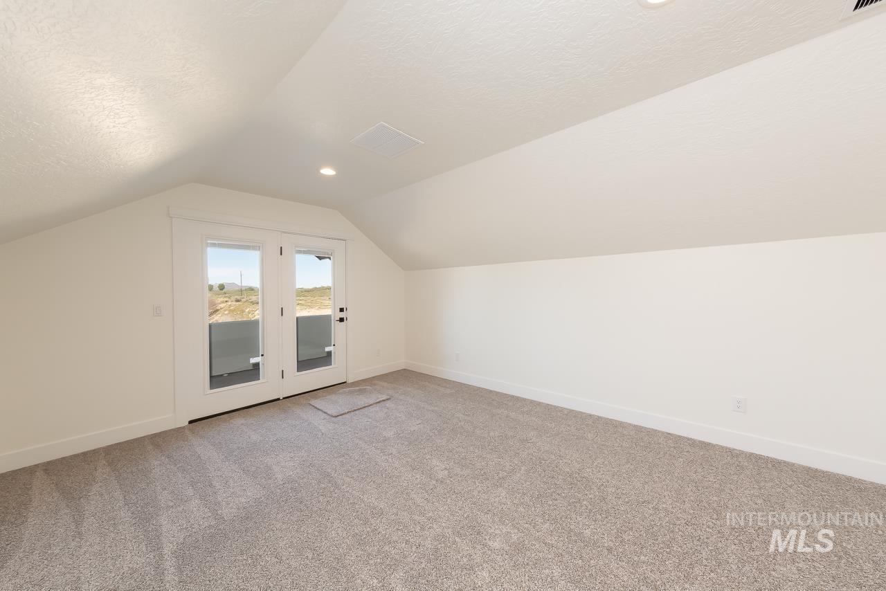 Bonus room featuring light colored carpet, a textured ceiling, and vaulted ceiling