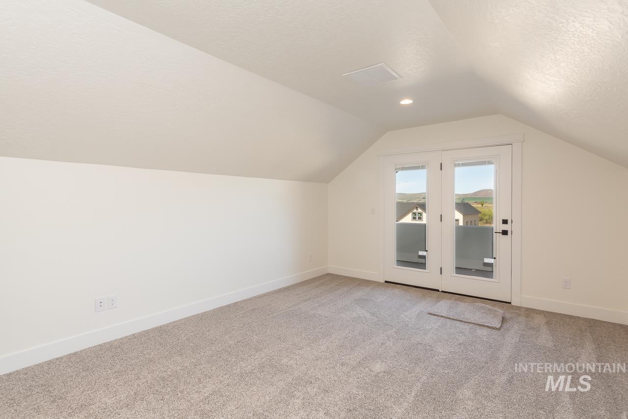 Bonus room with light colored carpet, a textured ceiling, and vaulted ceiling