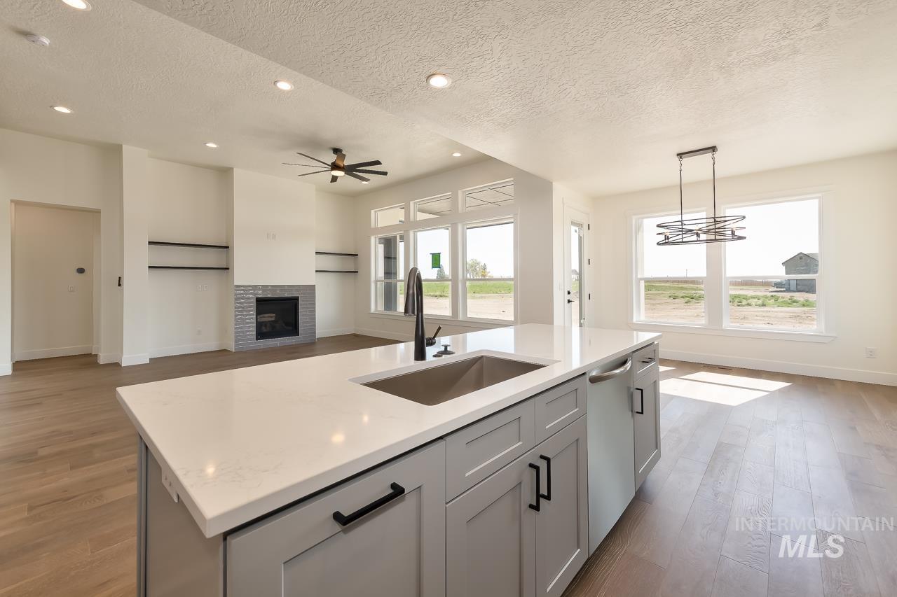 Kitchen with a textured ceiling, light wood-type flooring, gray cabinets, recessed lighting, and hanging light fixtures