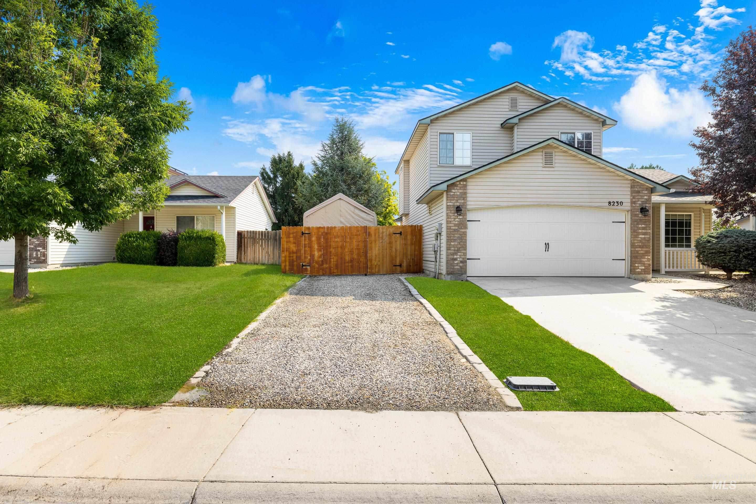 View of front of property featuring driveway, brick siding, a garage, and a gate