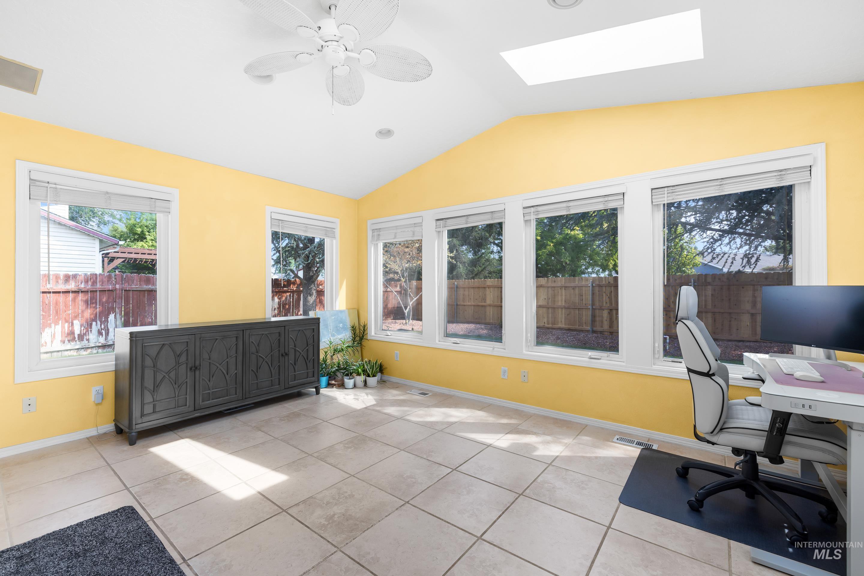 Office featuring lofted ceiling, light tile patterned floors, ceiling fan, a skylight, and recessed lighting
