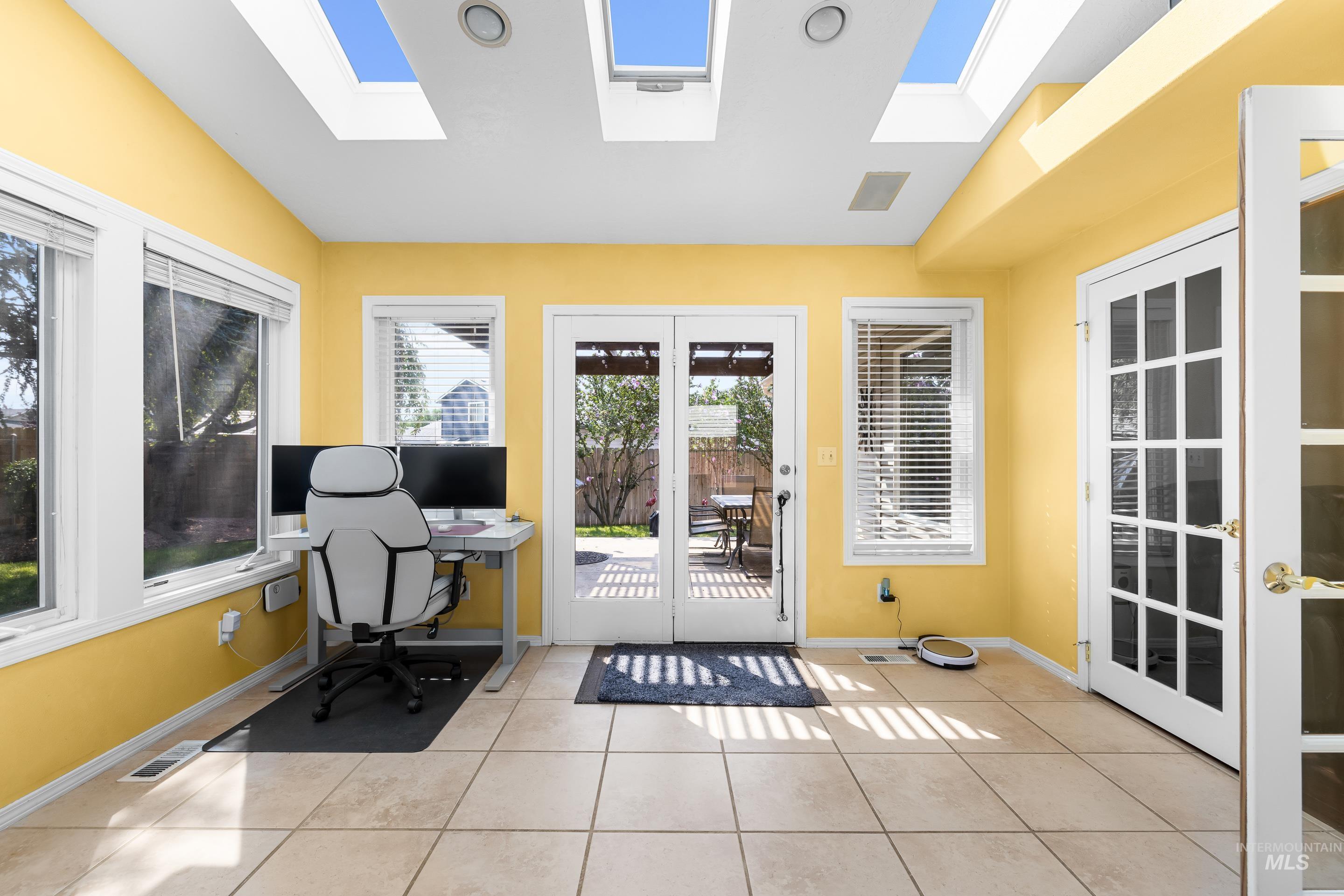 Doorway with tile patterned flooring, a skylight, vaulted ceiling, and a desk