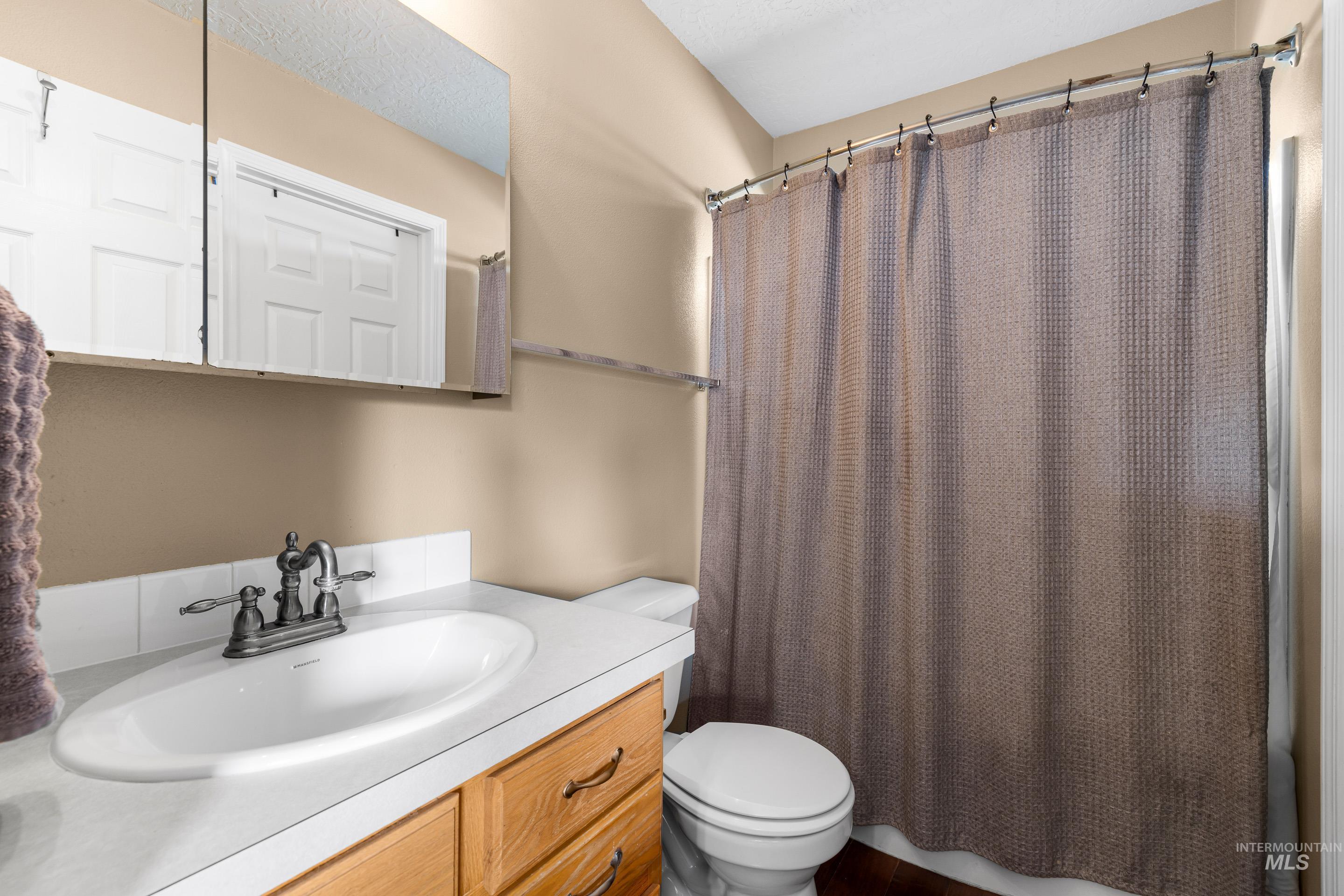 Full bathroom with vanity and a textured ceiling