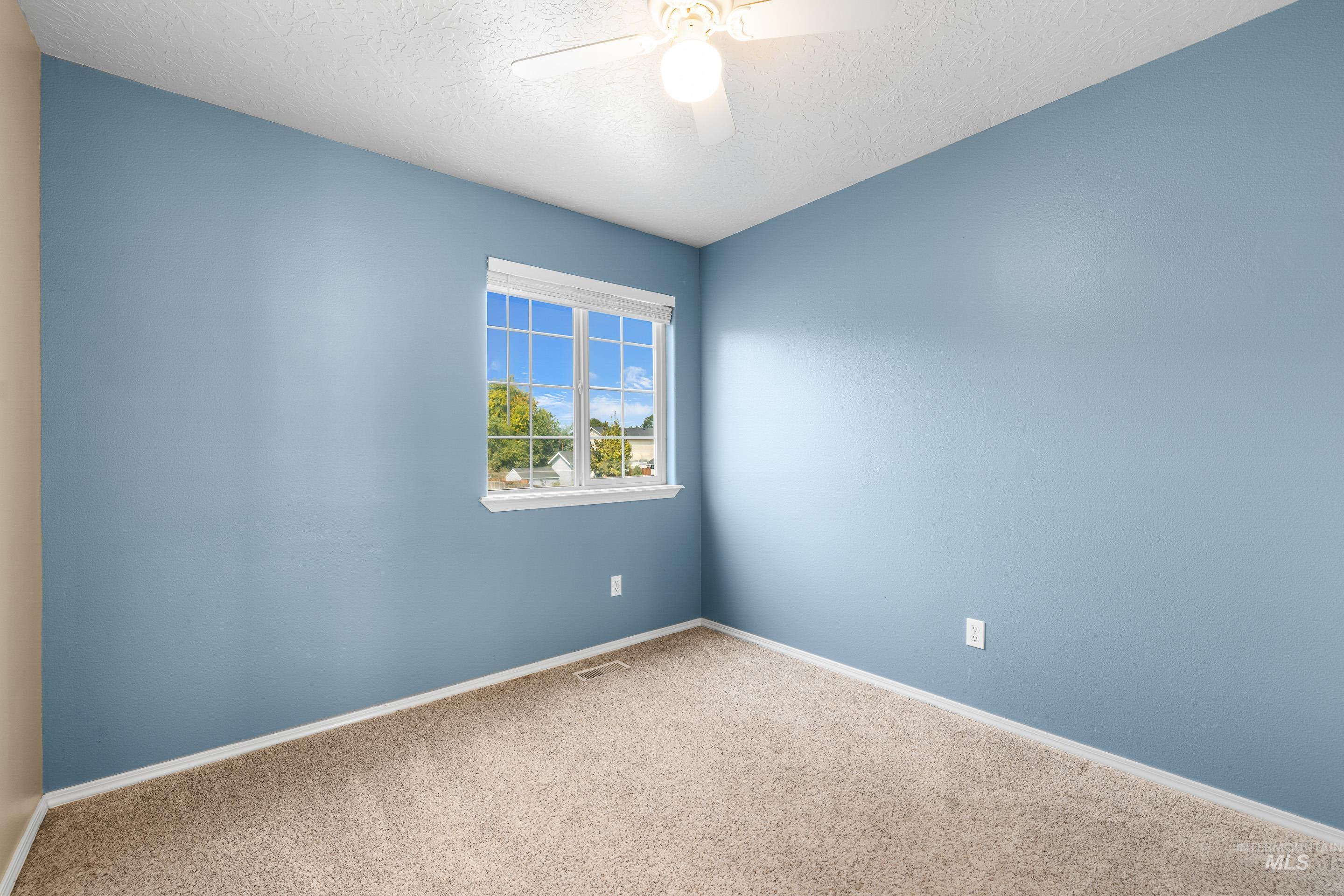 Carpeted spare room featuring a textured ceiling and ceiling fan