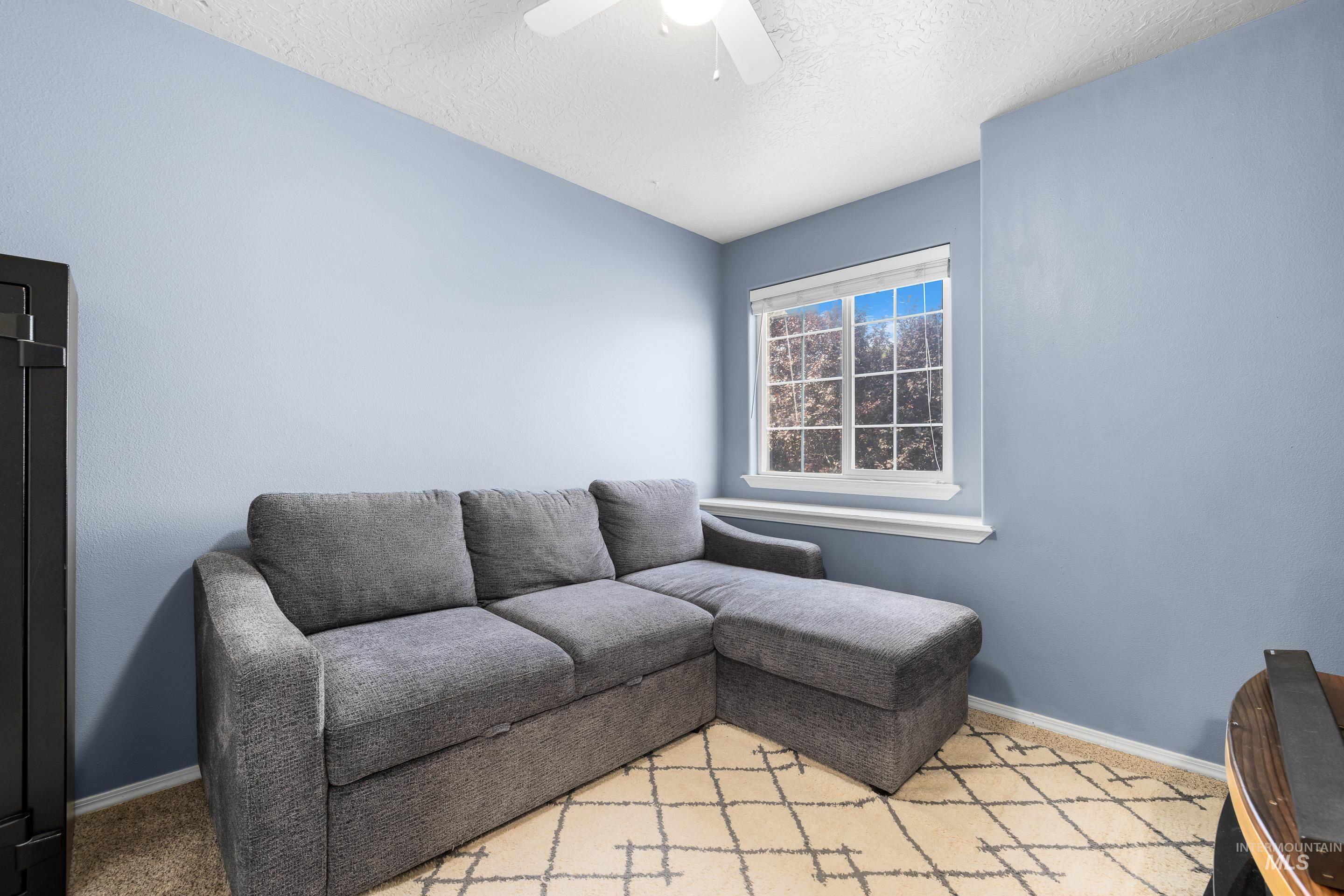 Carpeted living area with a textured ceiling and a ceiling fan
