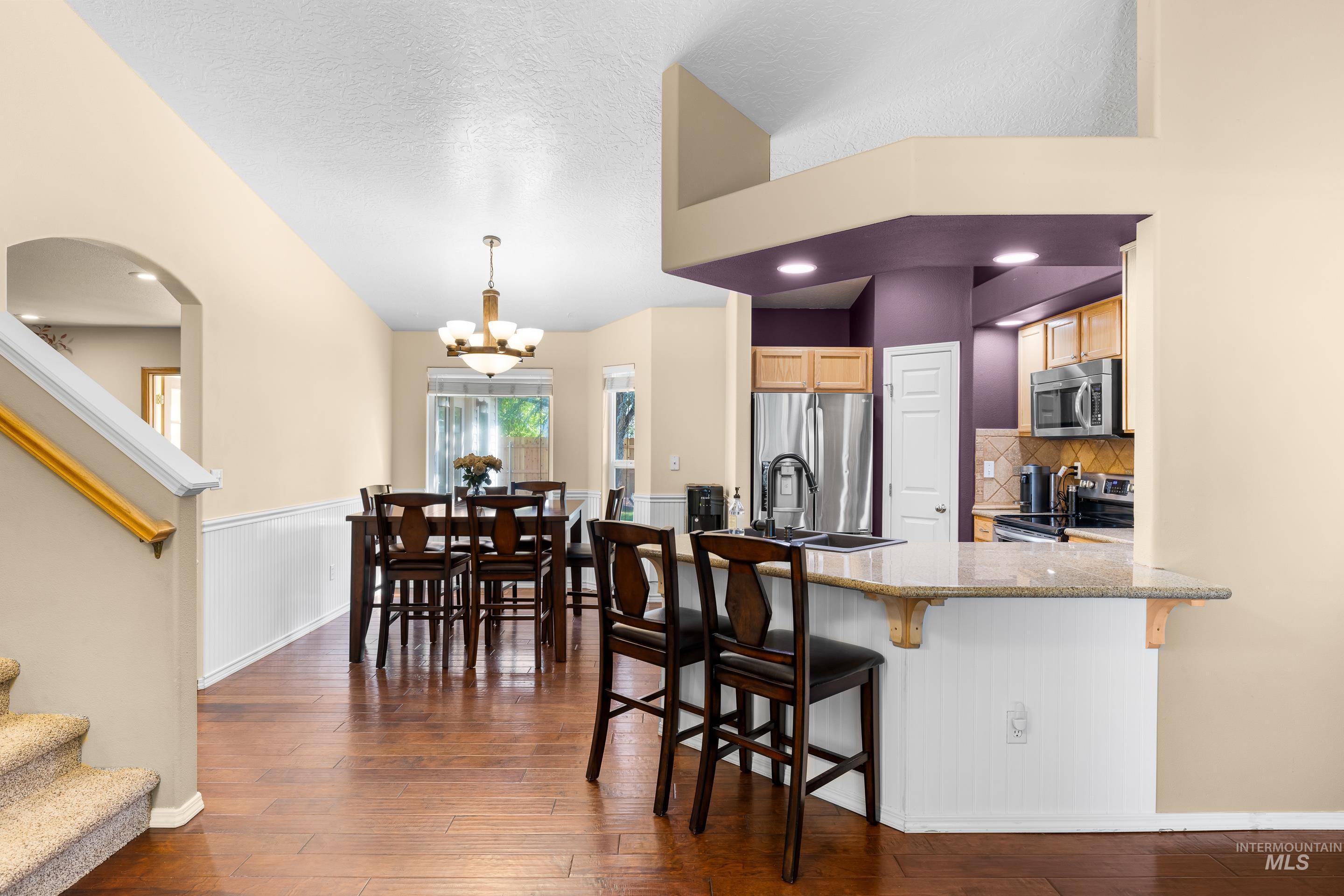 Kitchen with decorative backsplash, a kitchen breakfast bar, a peninsula, appliances with stainless steel finishes, and arched walkways