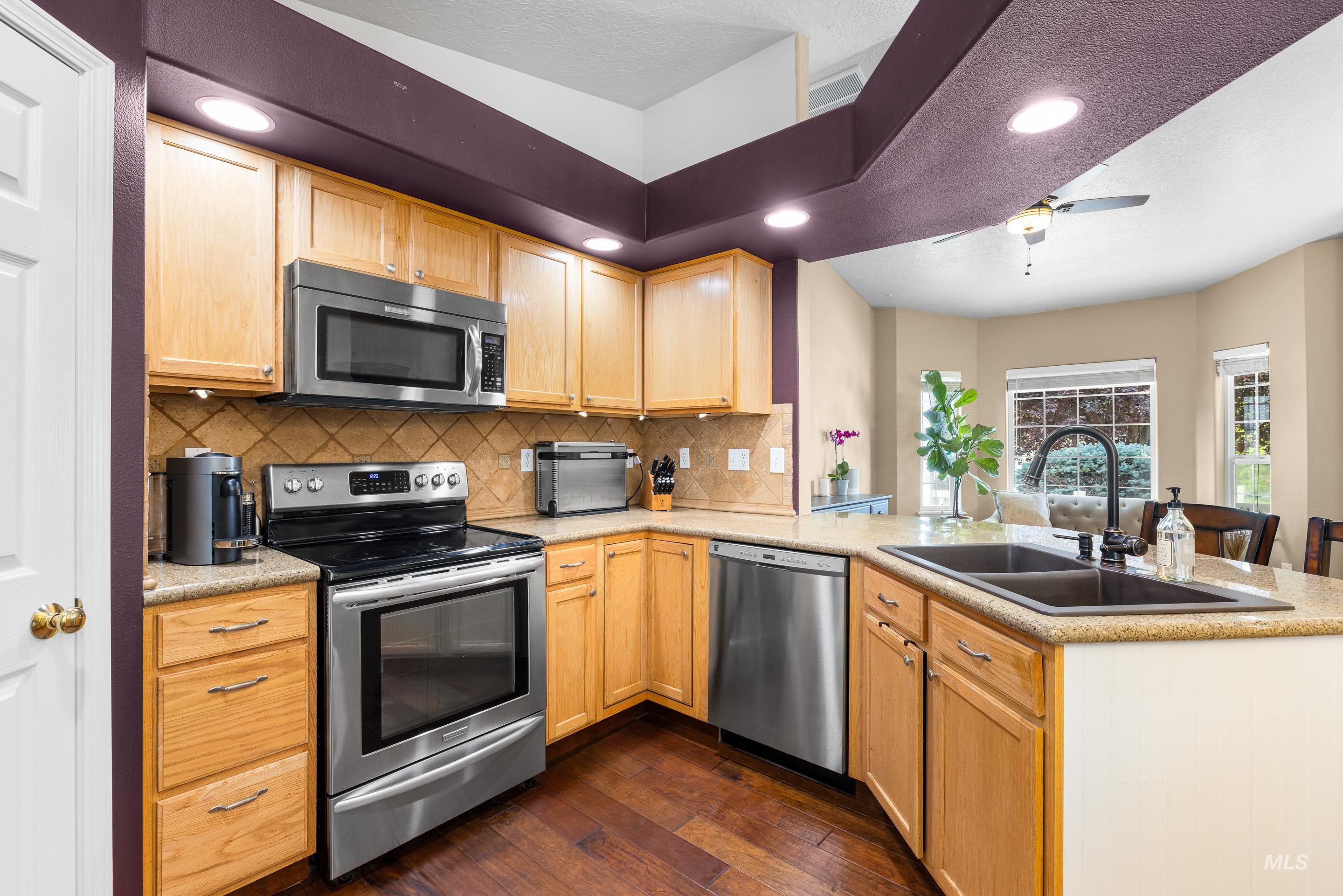 Kitchen with appliances with stainless steel finishes, tasteful backsplash, light brown cabinets, and recessed lighting