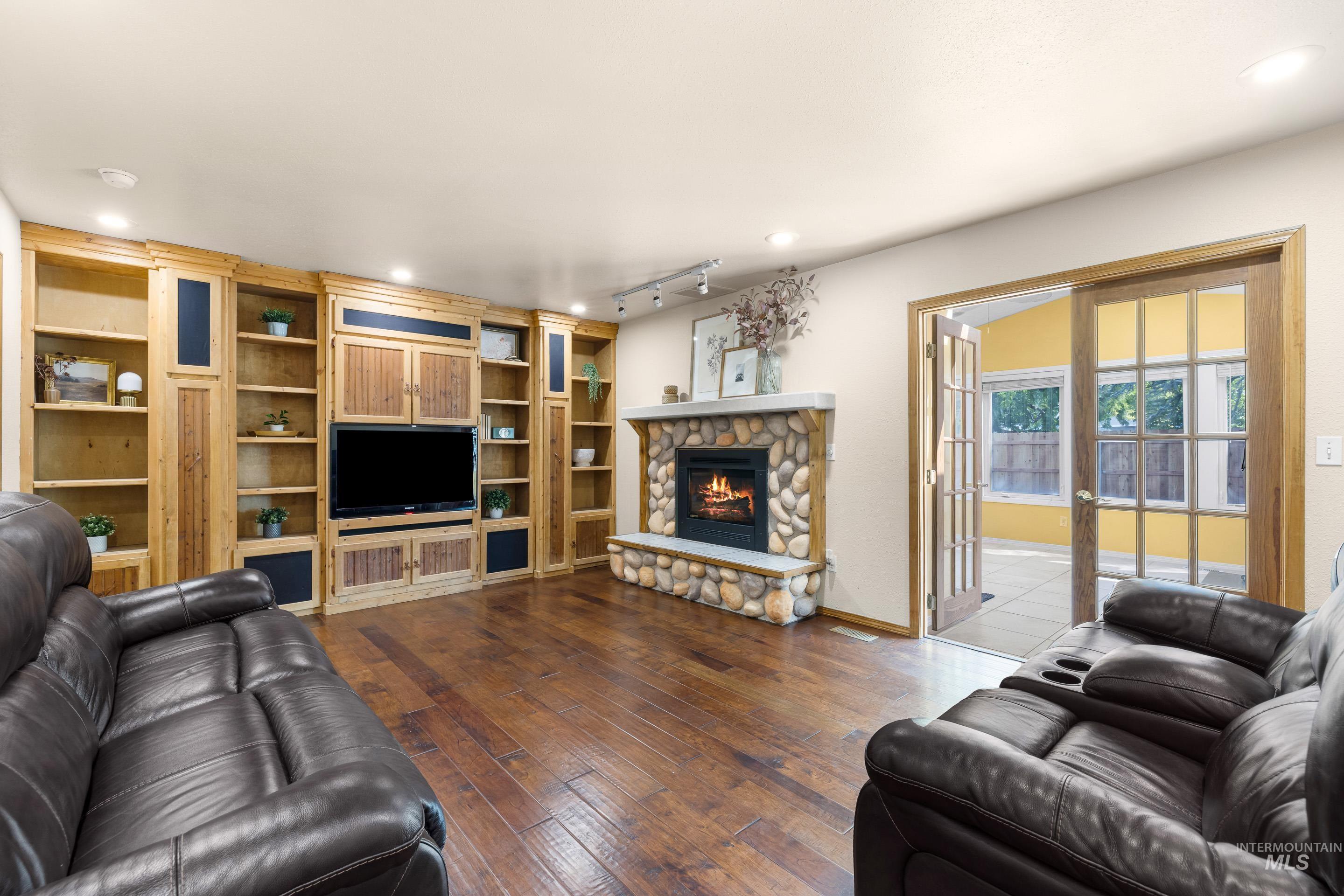 Living area with a fireplace, dark wood finished floors, recessed lighting, rail lighting, and french doors
