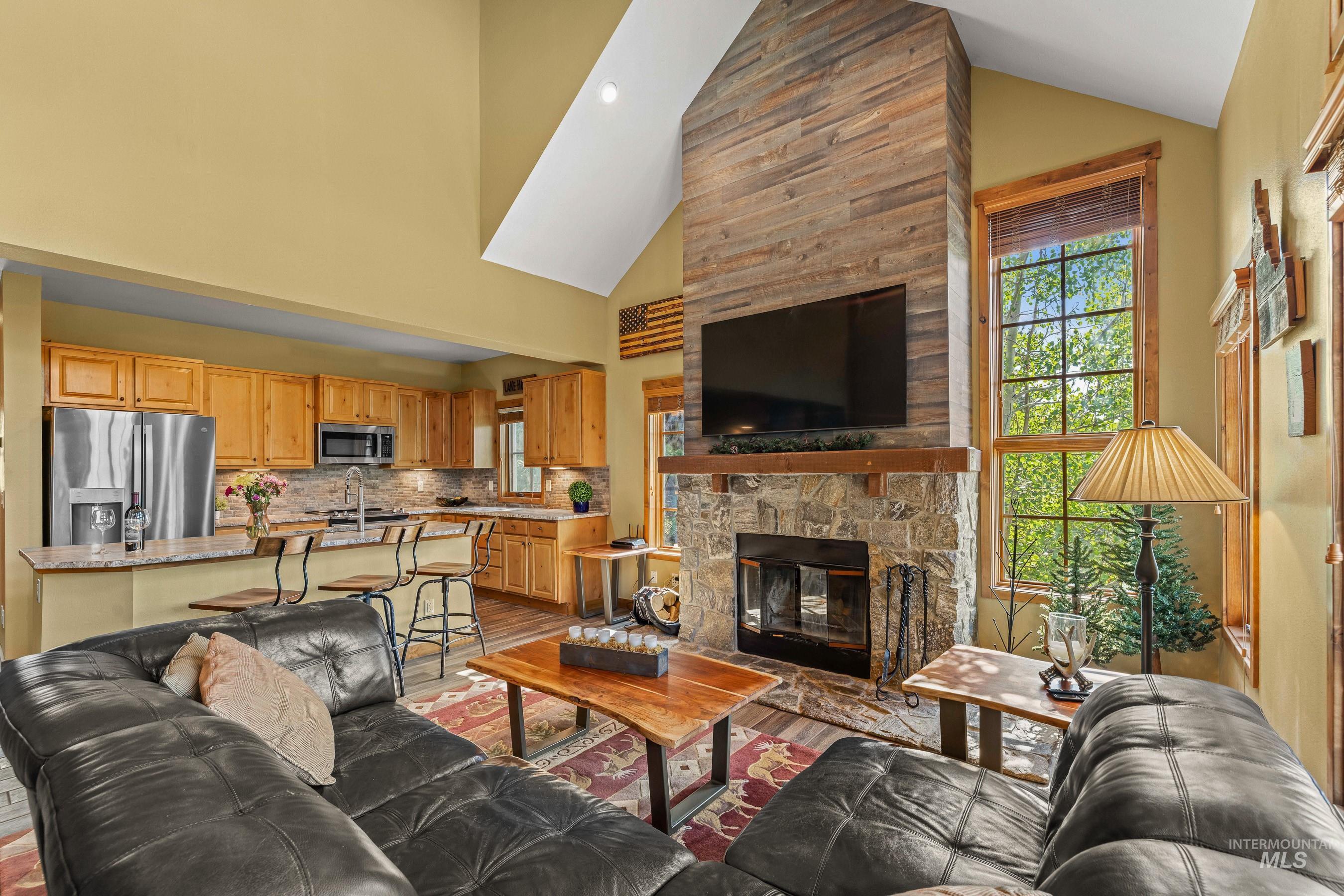 Living area with high vaulted ceiling, new tiled floors, and a fireplace