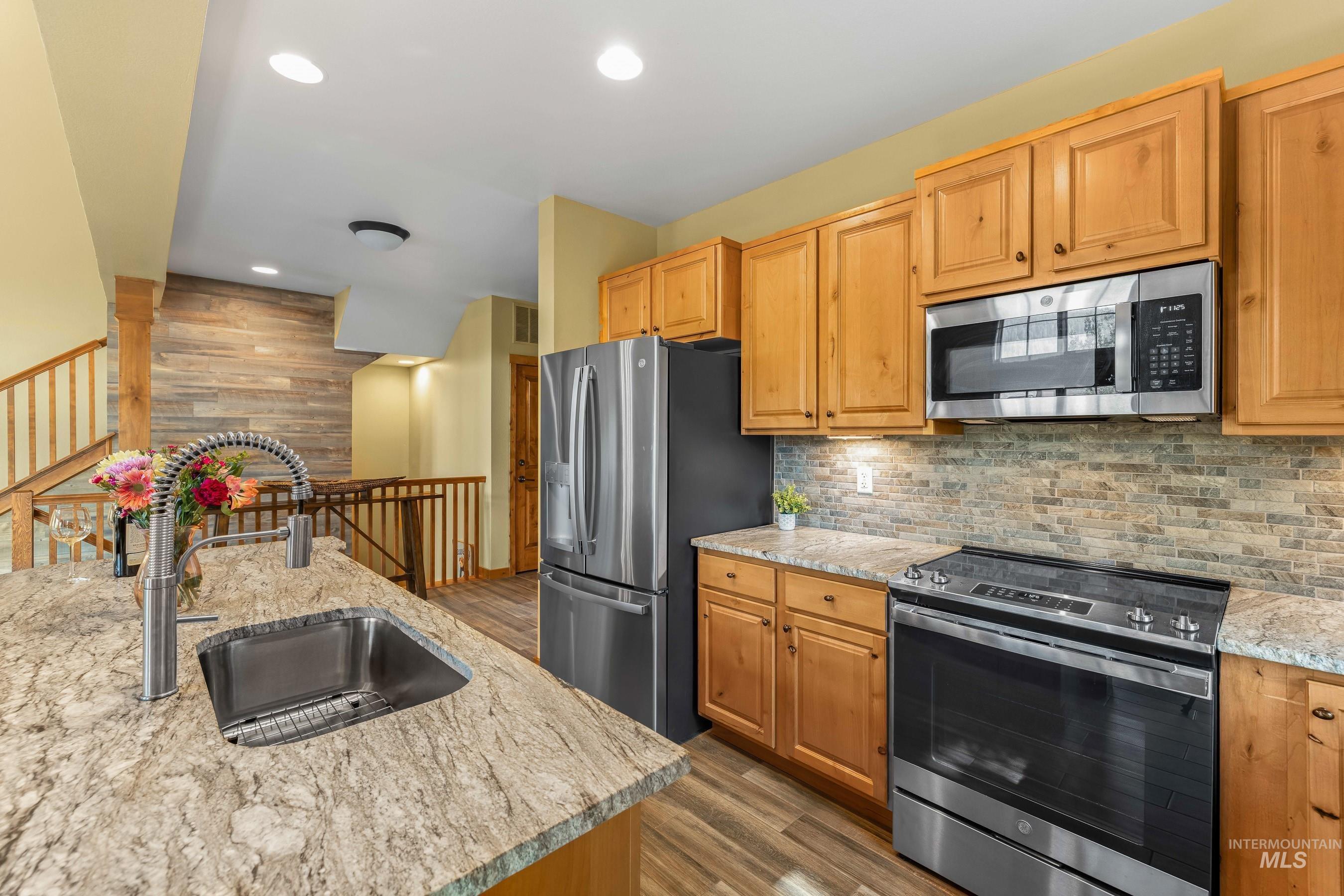 Kitchen with appliances with stainless steel finishes,  newly finished  floors, decorative backsplash,  and new granite countertops