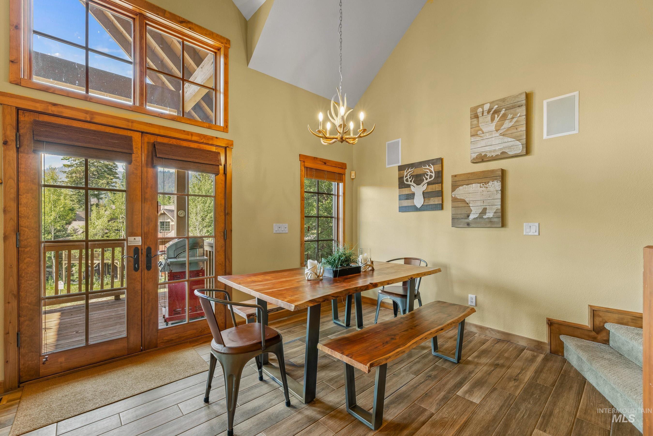 Dining space featuring high vaulted ceiling, newly finished floors, and a chandelier