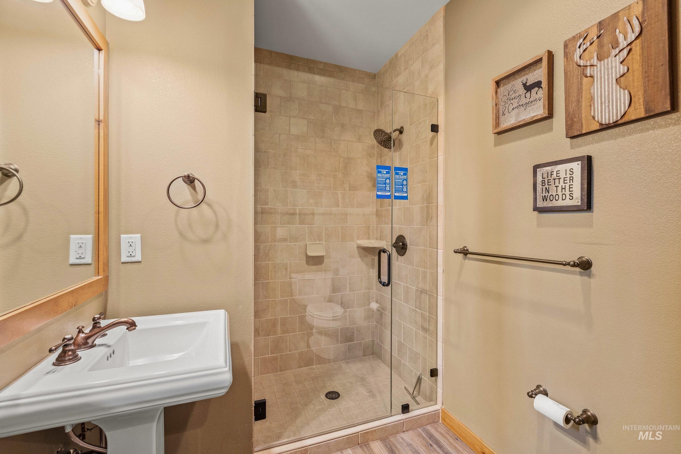 Main level full bathroom with a shower stall and a sink