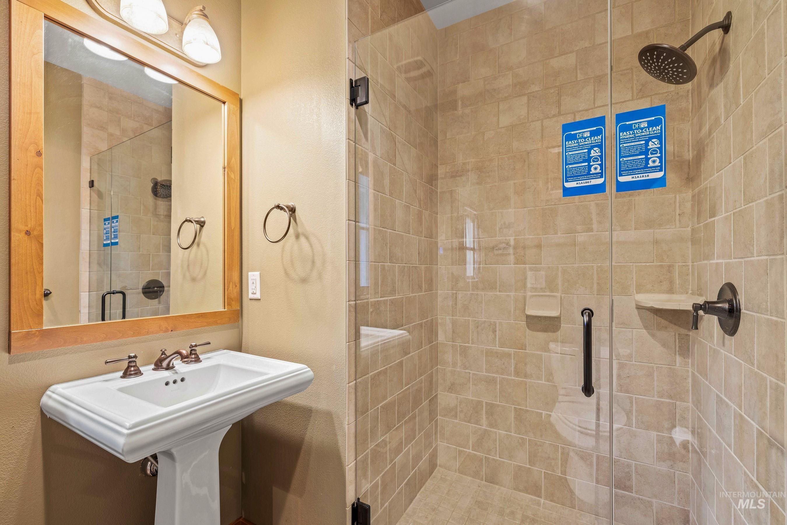 Main level full bathroom with a shower stall and a sink