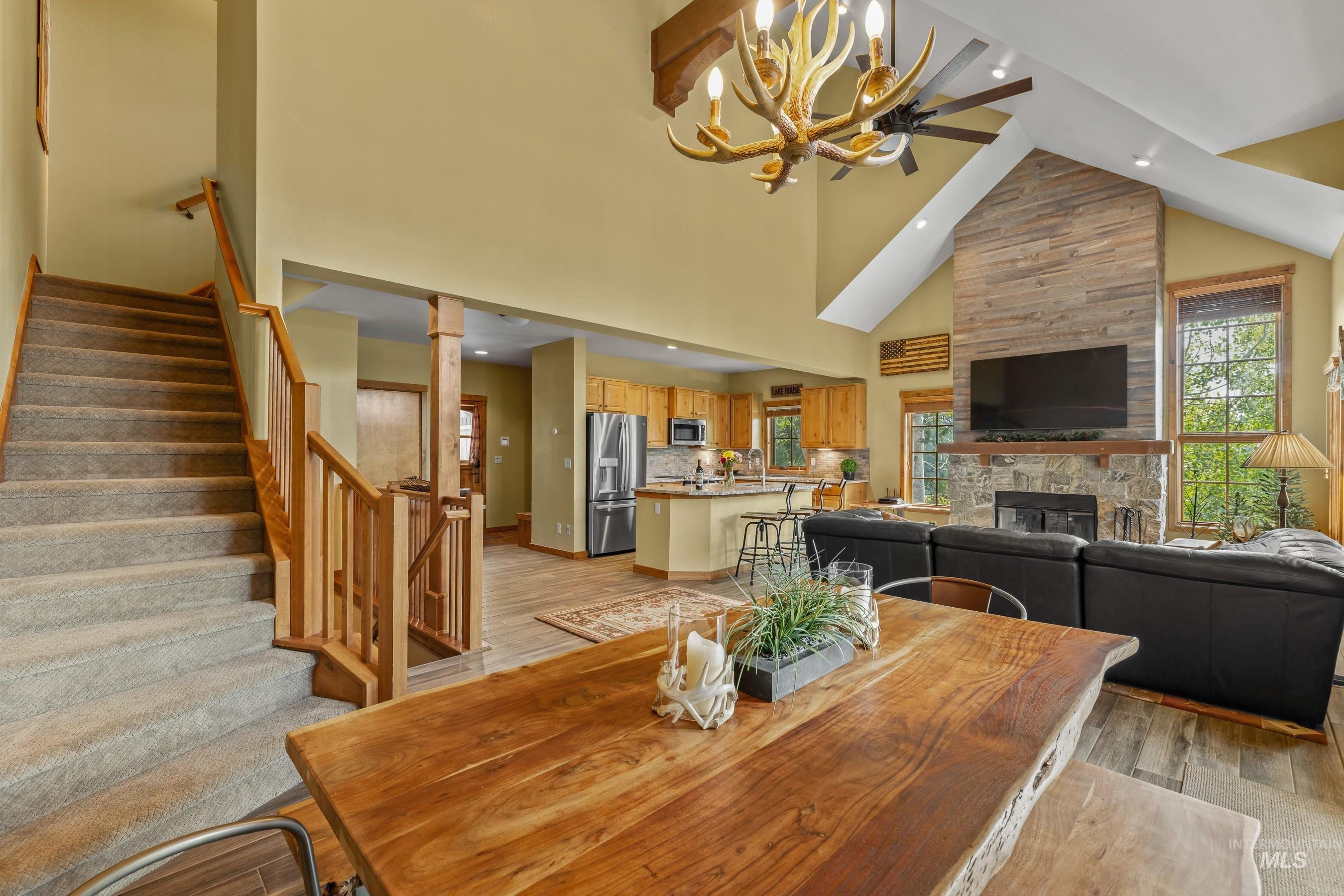 Dining space with a fireplace, newly carpeted stairway, newly finished flooring, high vaulted ceiling, and a chandelier