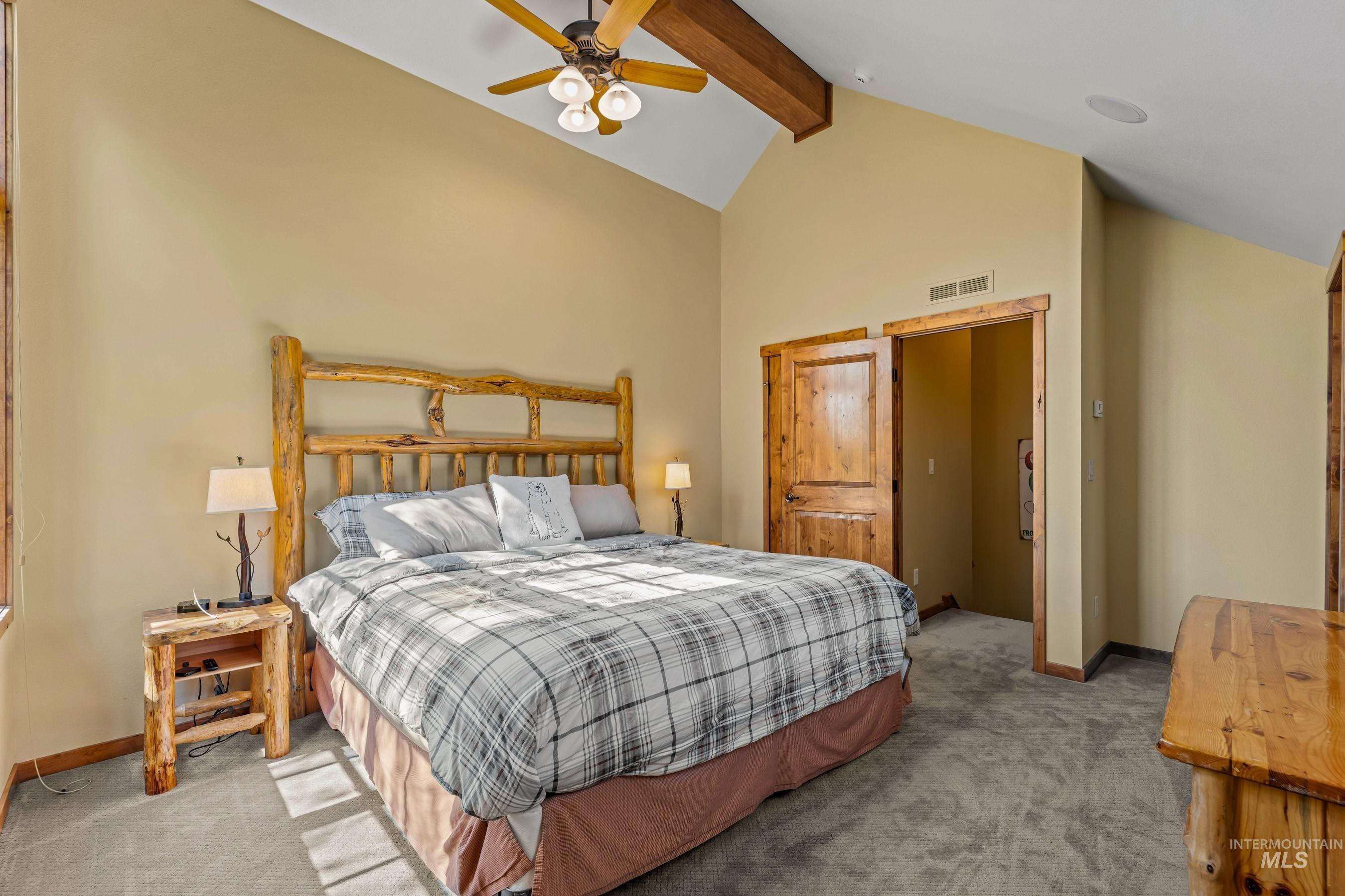 Newly carpeted primary featuring beam ceiling, high vaulted ceiling, and ceiling fan