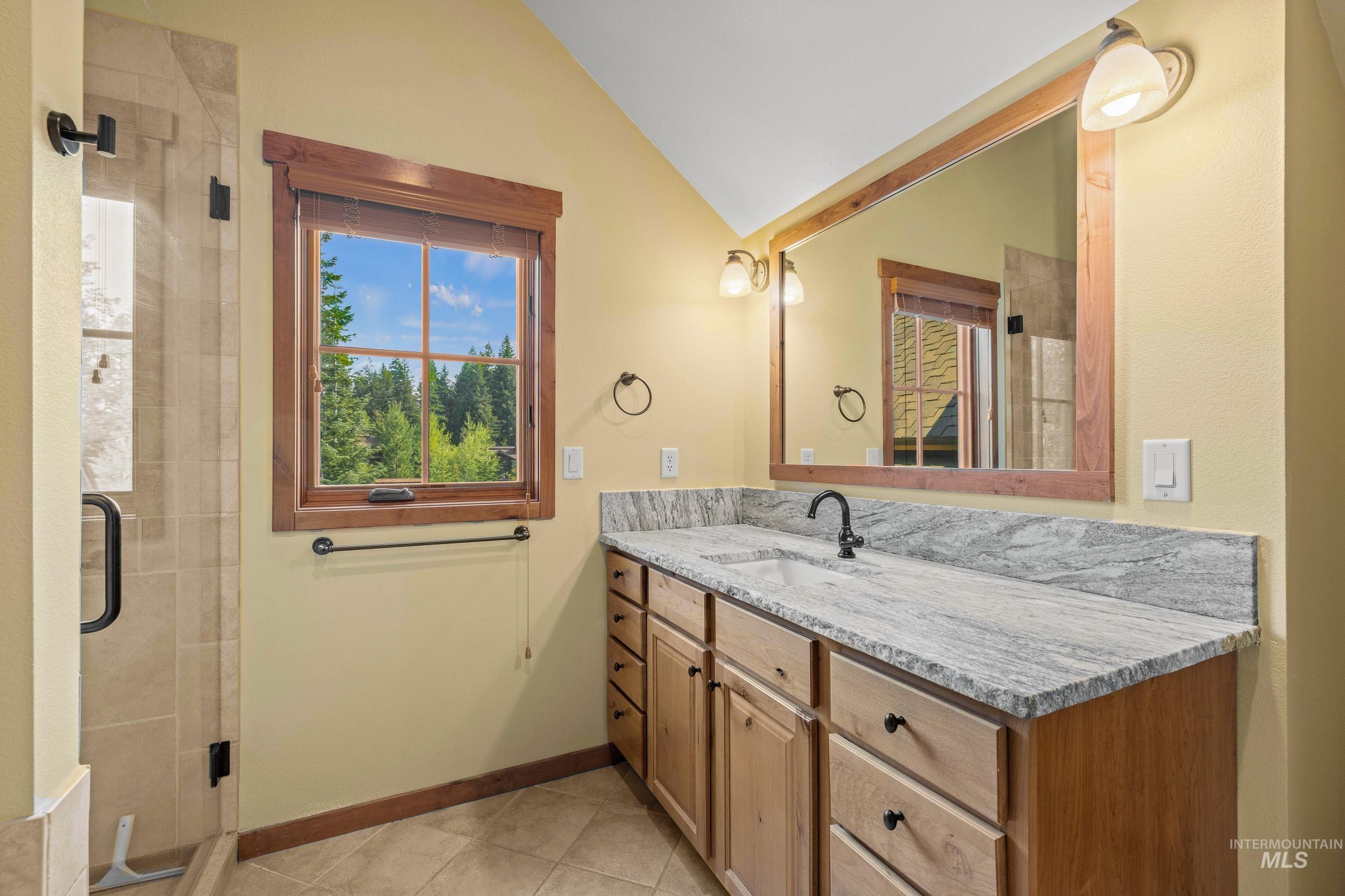 Primary bathroom with a stall shower, bathtub, new vanity countertop, and lofted ceiling