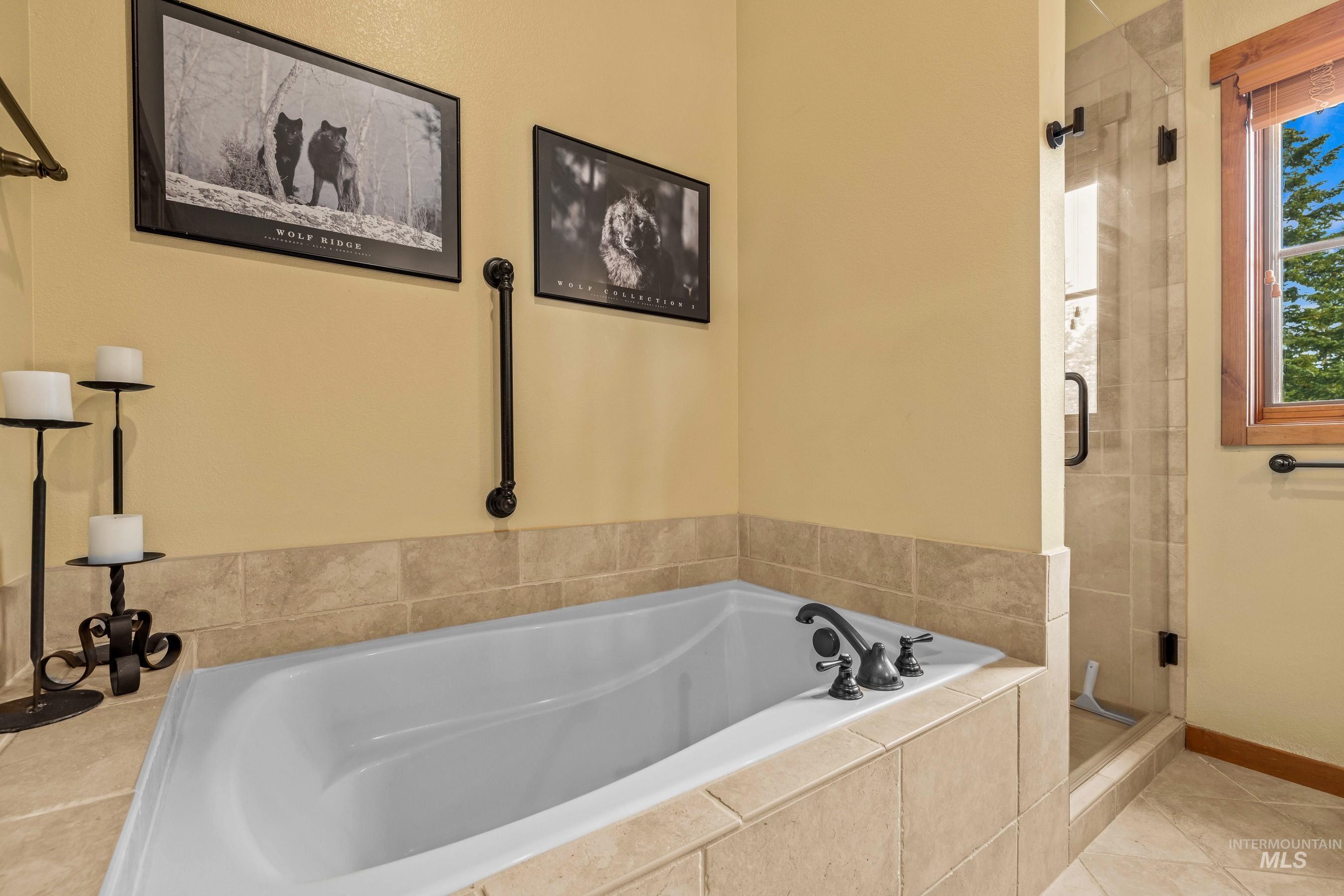 Primary bathroom with a stall shower, bathtub, new vanity countertop, and lofted ceiling