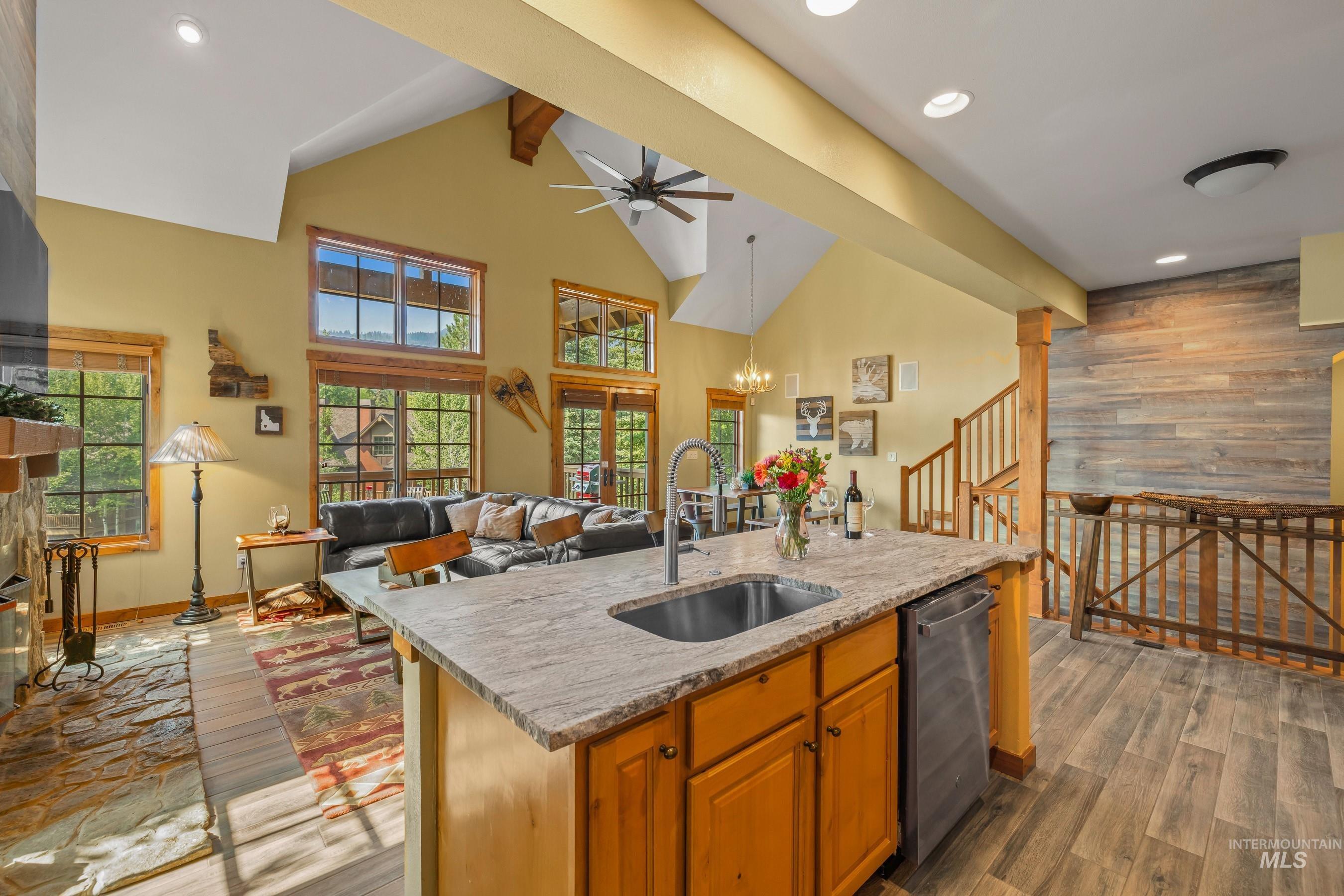 Kitchen featuring brown cabinetry, light stone countertops, recessed lighting, wood finished floors, and beam ceiling