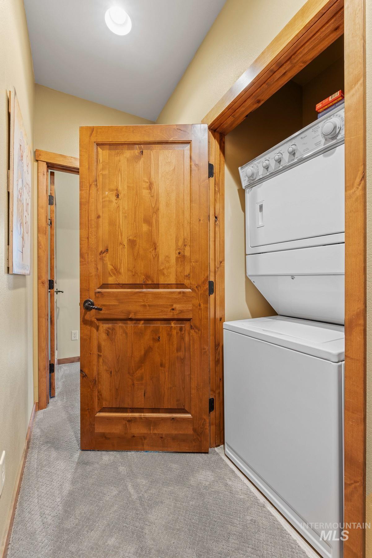 Laundry room with carpet floors and stacked washer / drying machine