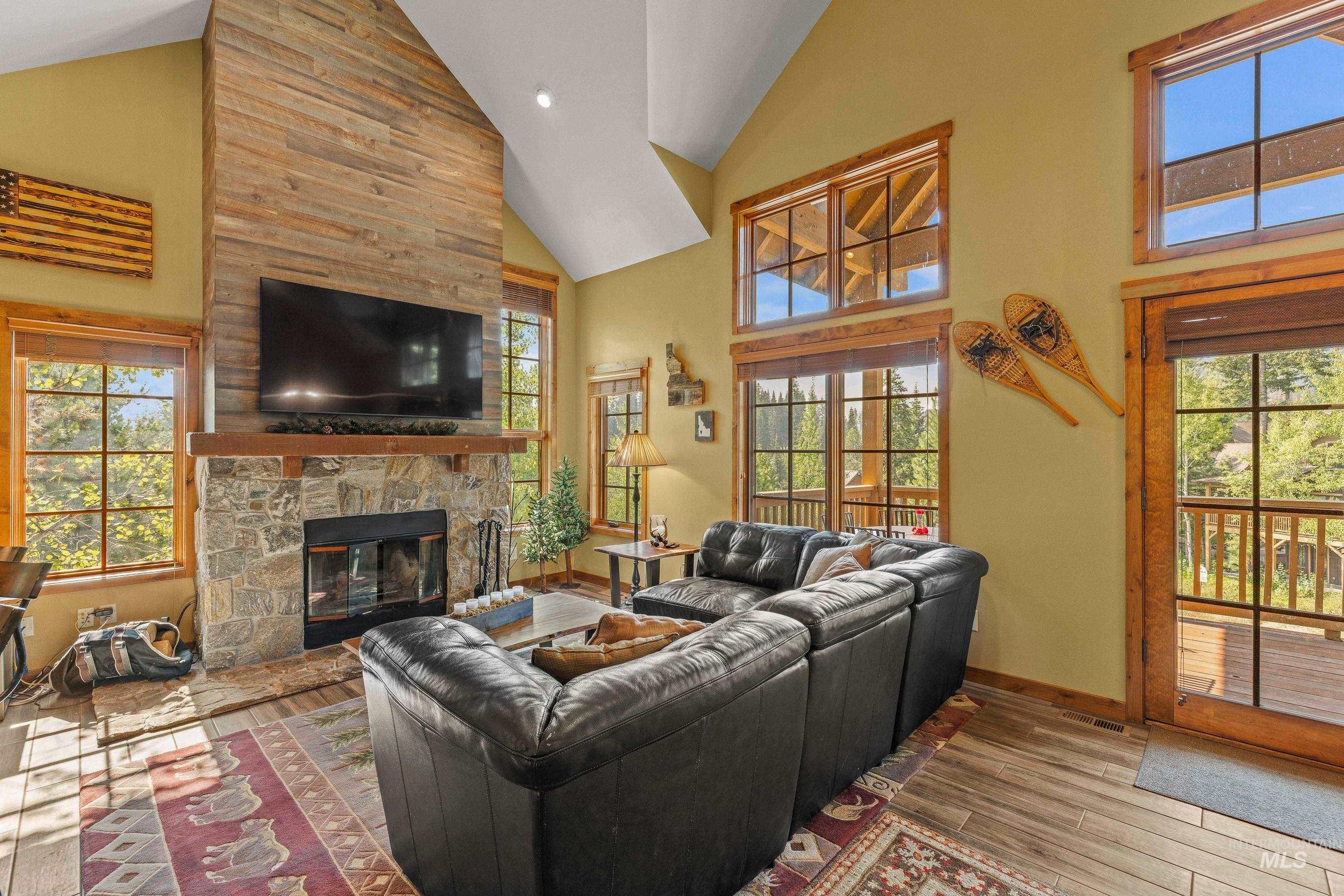 Living room featuring high vaulted ceiling, with newly finished floors, a stone fireplace, and recessed lighting