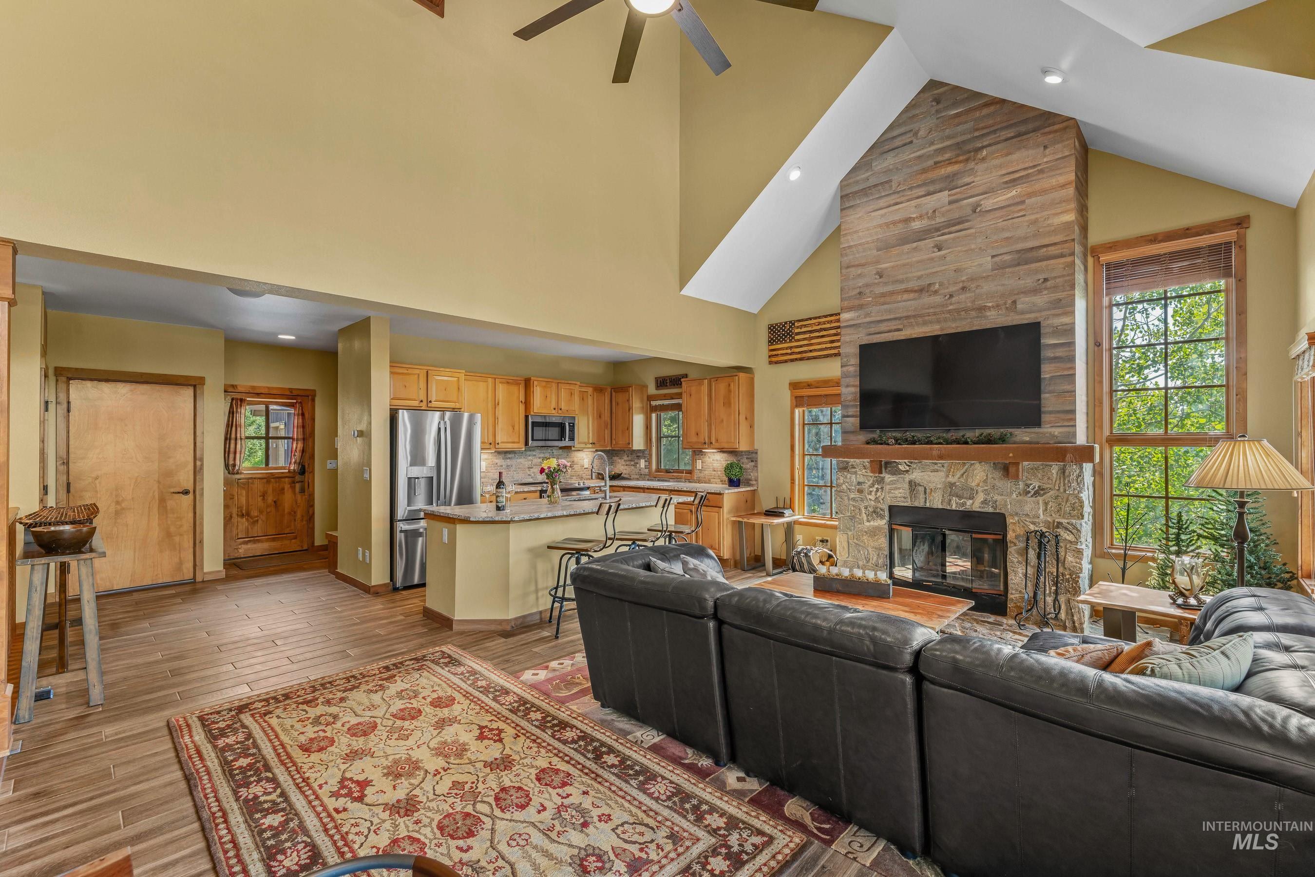 Living area with a fireplace, newly finished tile floors, high vaulted ceiling, ceiling fan, and recessed lighting