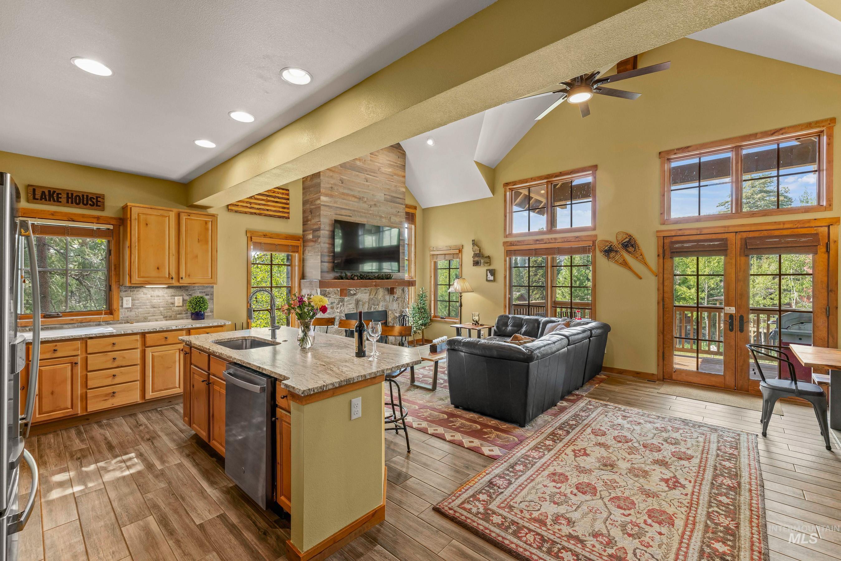 Kitchen featuring open floor plan, new granite countertops, a kitchen island with sink, healthy amount of natural light, and high vaulted ceiling