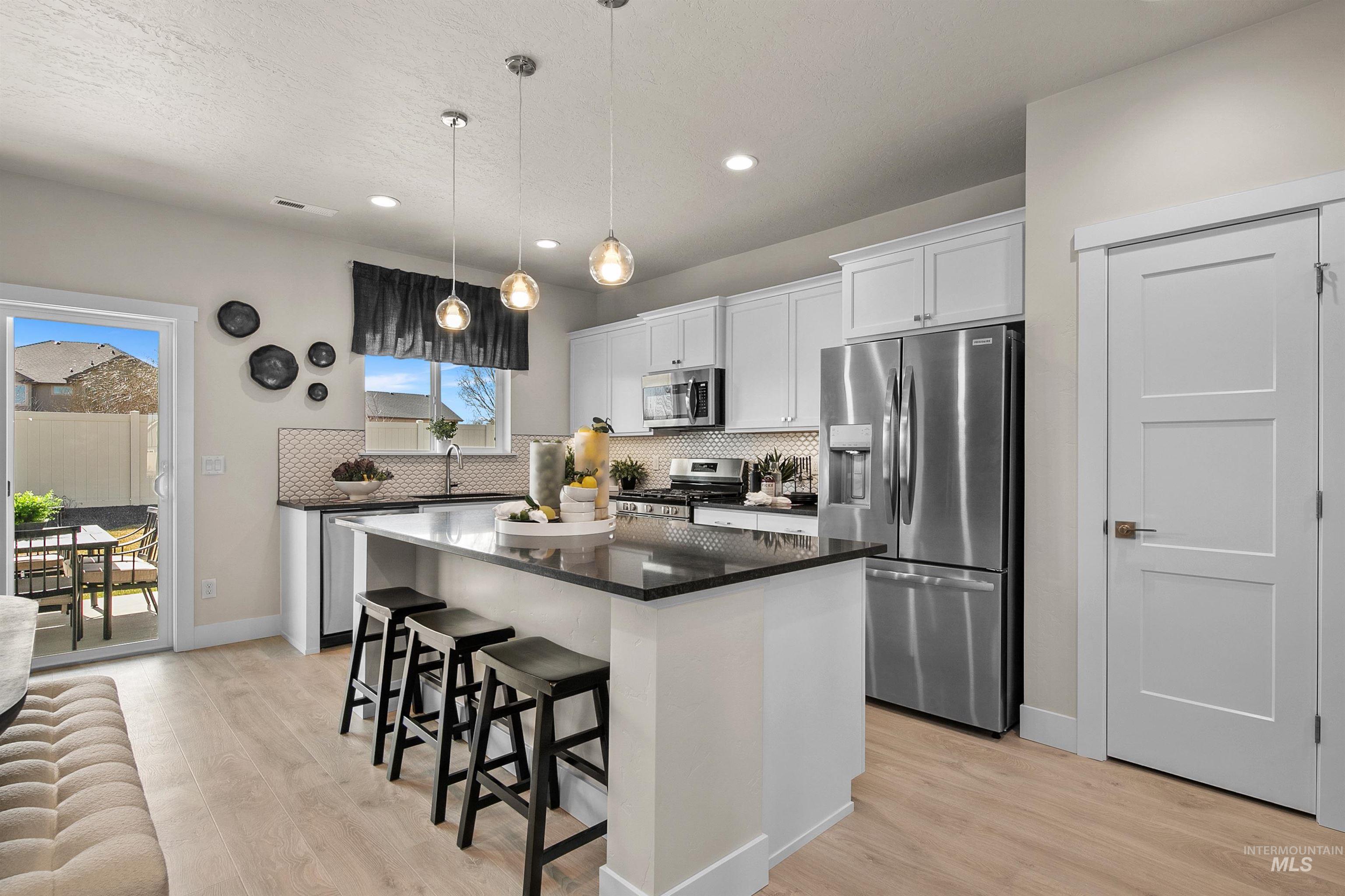Kitchen with appliances with stainless steel finishes, a center island, a kitchen breakfast bar, white cabinets, and dark stone counters