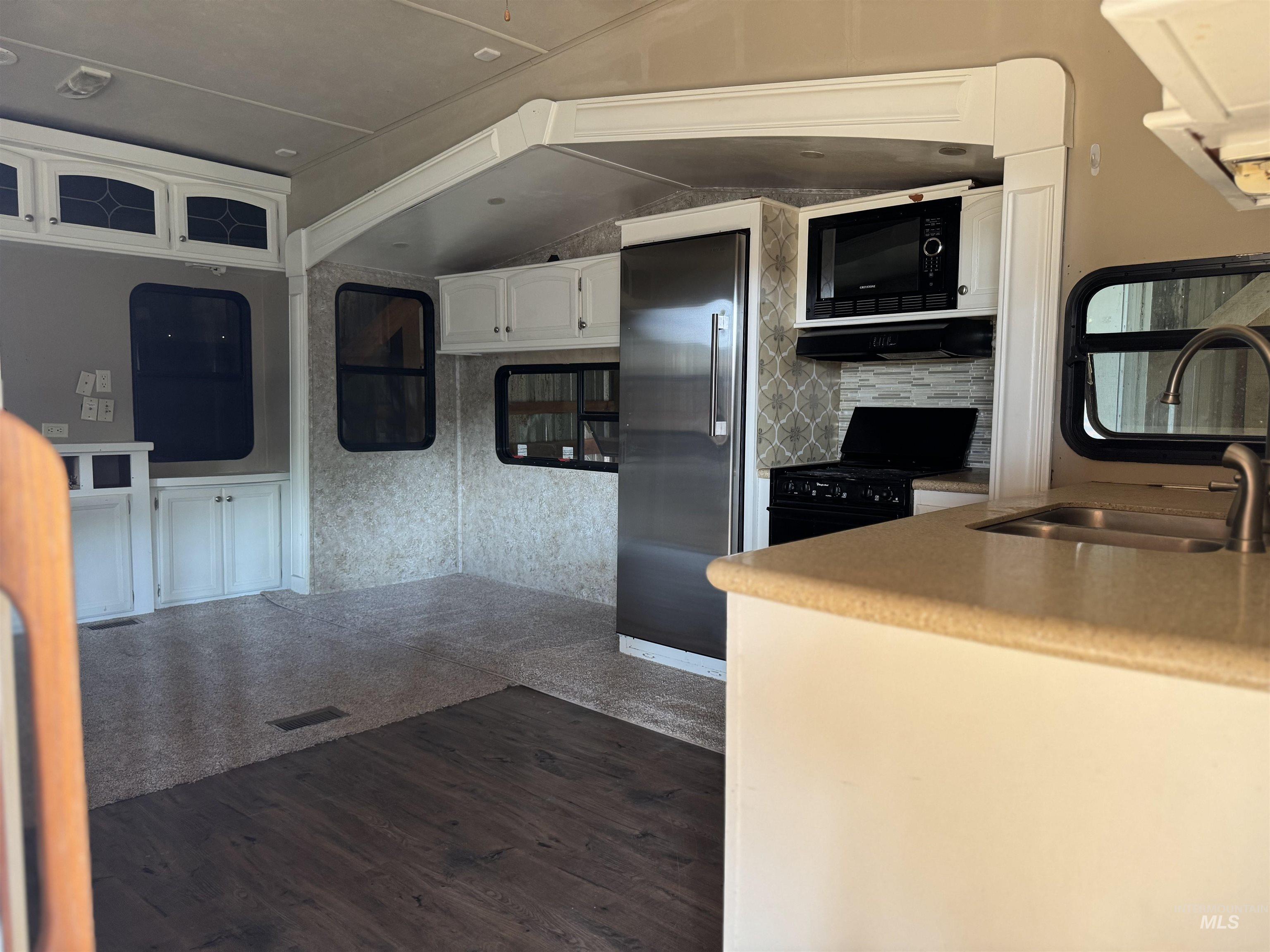 Kitchen with dark wood-style floors, black appliances, and white cabinets