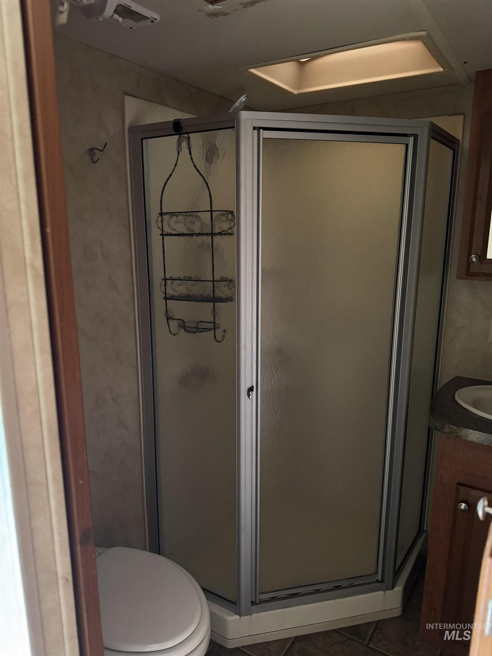 Bathroom featuring vanity, a shower stall, and dark tile patterned flooring