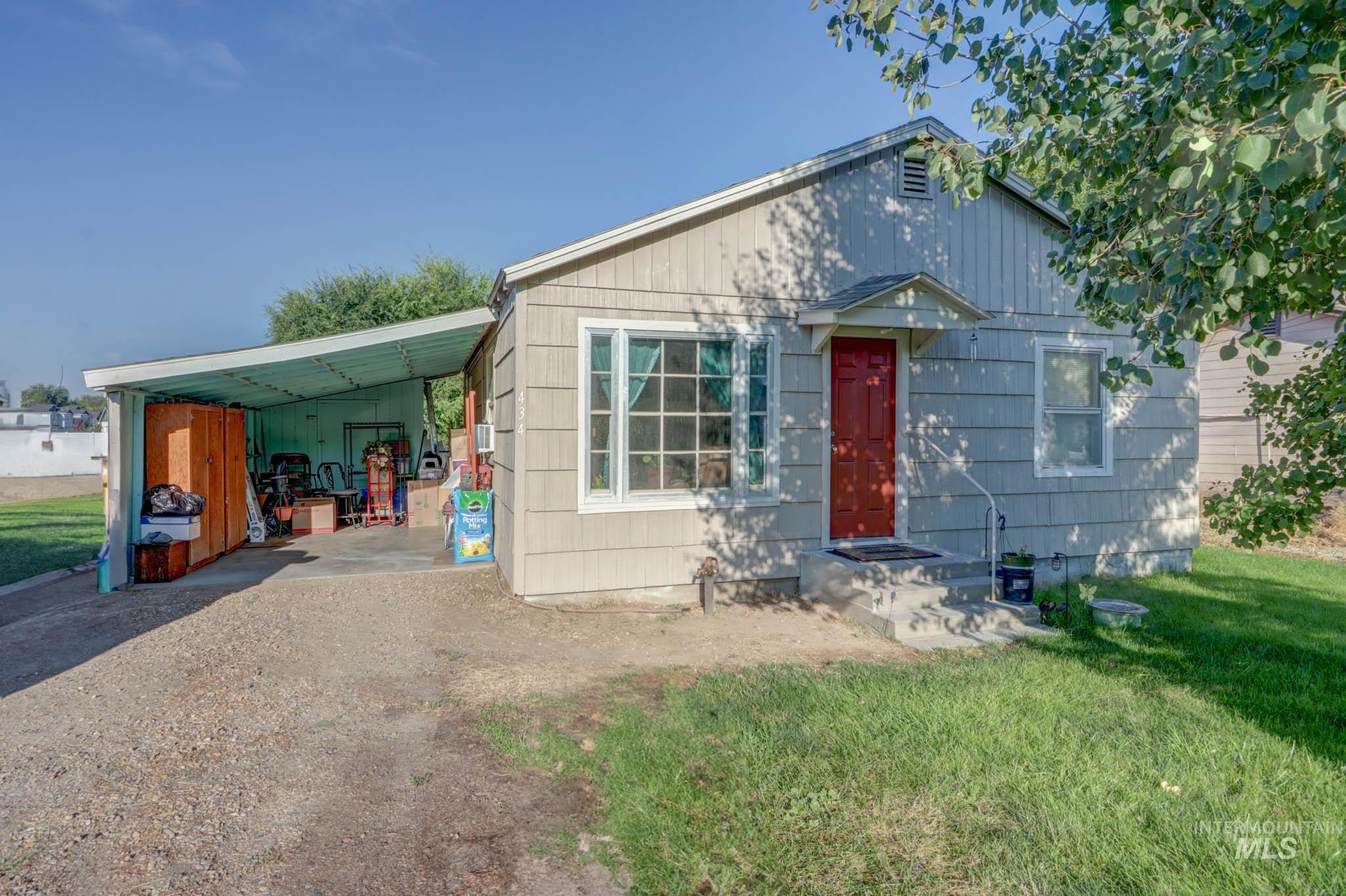 View of front facade featuring an attached carport, a front lawn, and dirt driveway